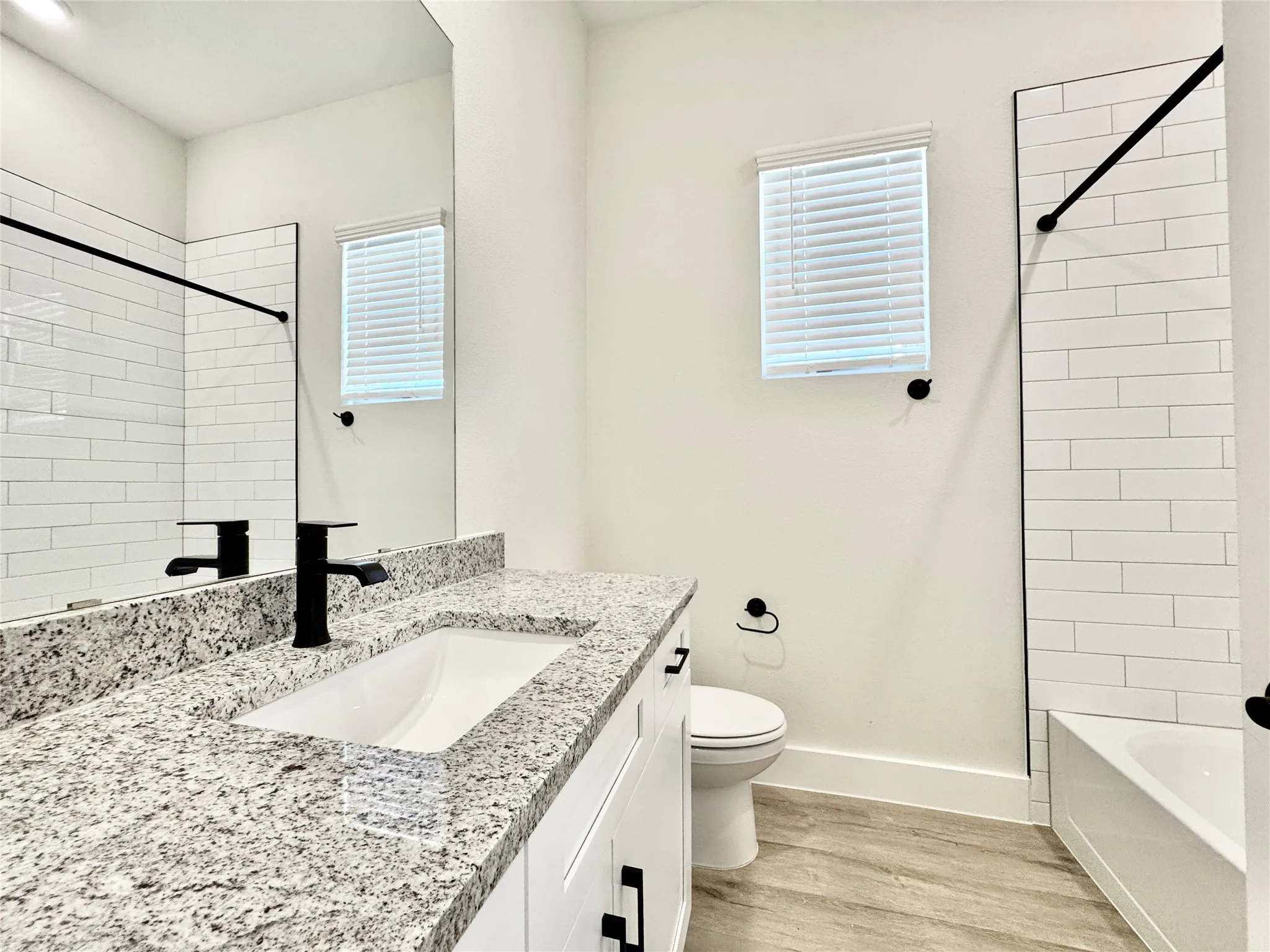 Full bath with wood finished floors, baseboards, toilet, vanity, and shower / bathtub combination