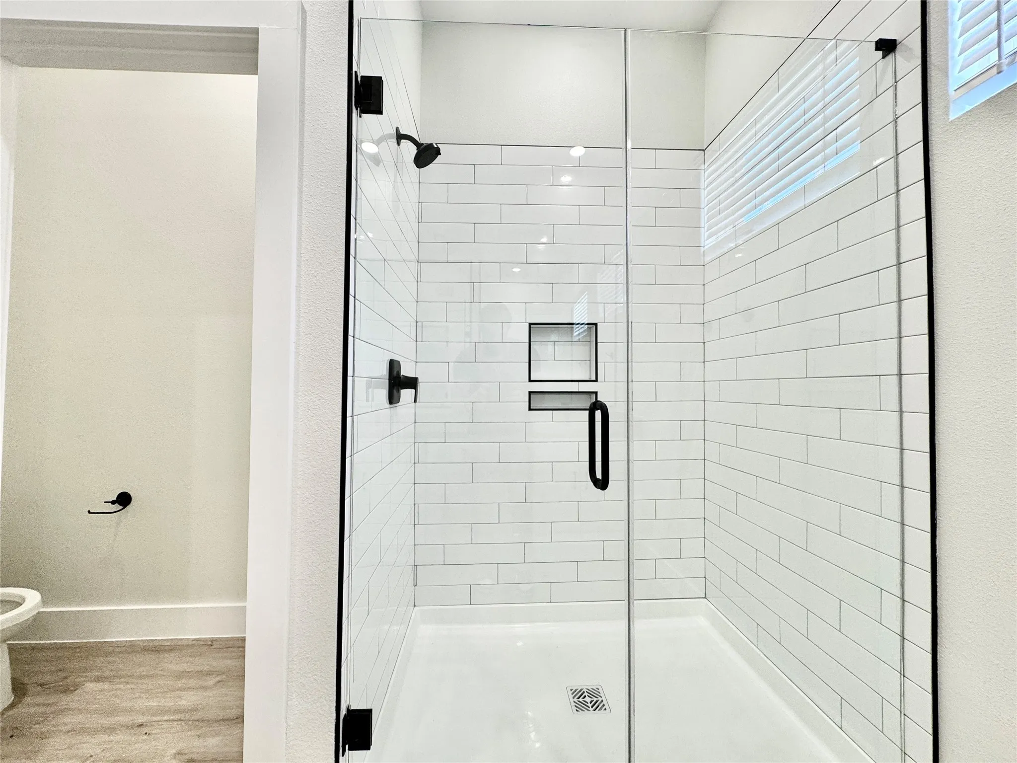 Bathroom with wood finished floors, a shower stall, toilet, and baseboards