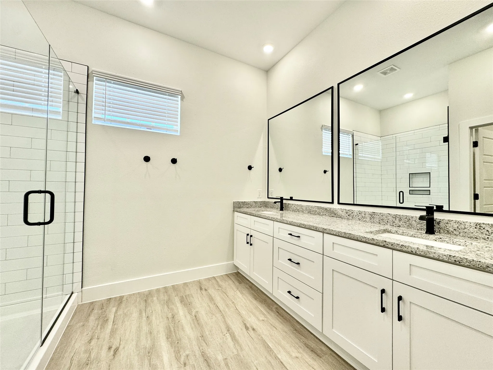 Bathroom featuring wood finished floors, plenty of natural light, a shower stall, and recessed lighting