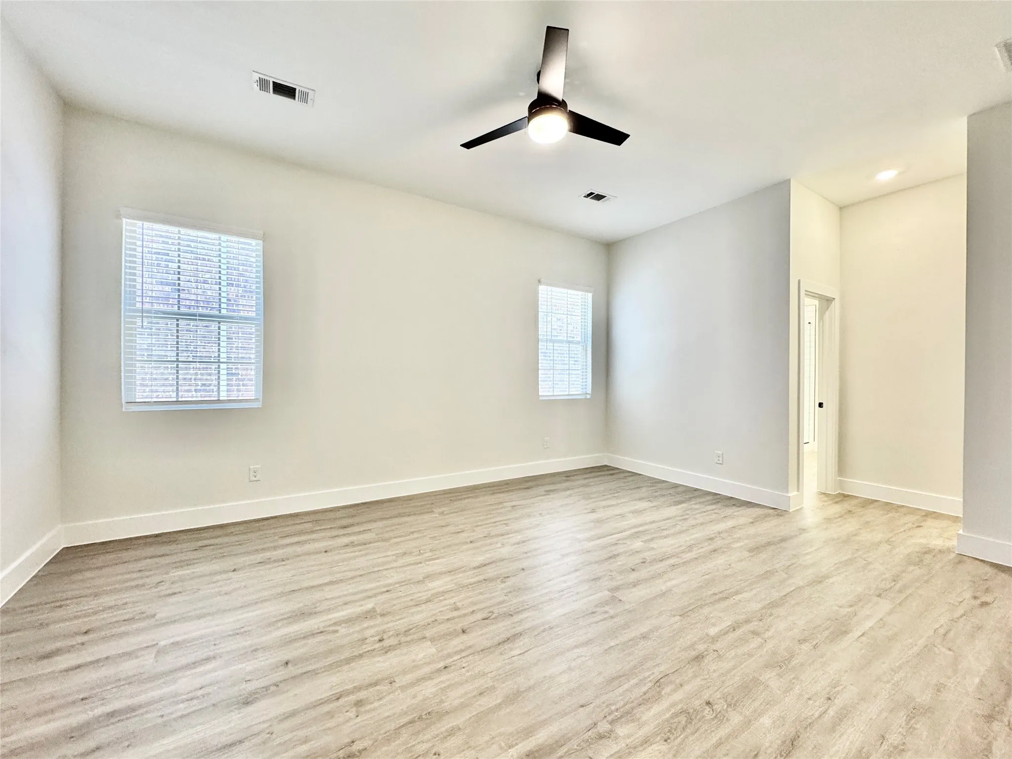 Spare room with wood finished floors, a ceiling fan, and baseboards
