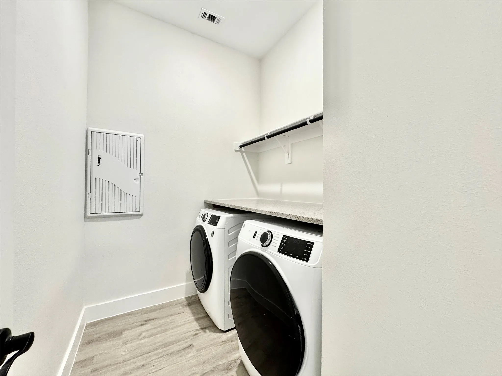 Clothes washing area with washer and dryer, light wood finished floors, and baseboards