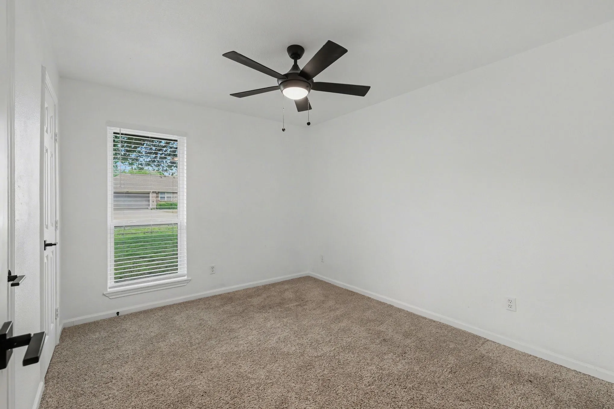 Carpeted room with ceiling fan and light-colored walls