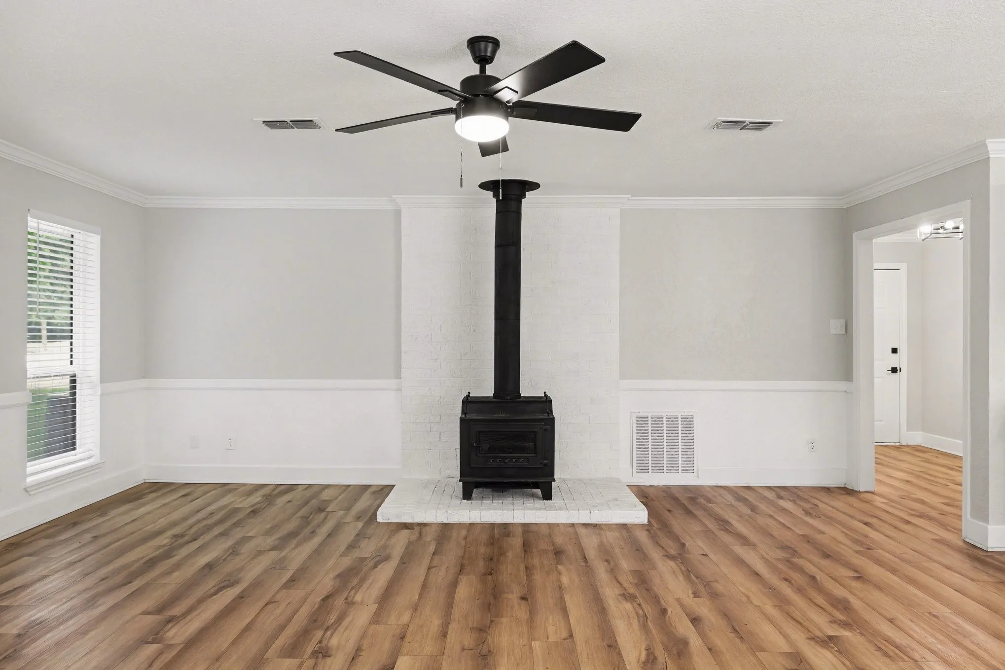 Living room view toward stove; plank flooring and ceiling fan
