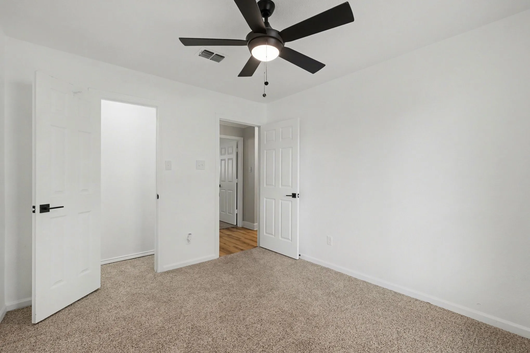 Bedroom with carpet, white walls, and ceiling fan with light