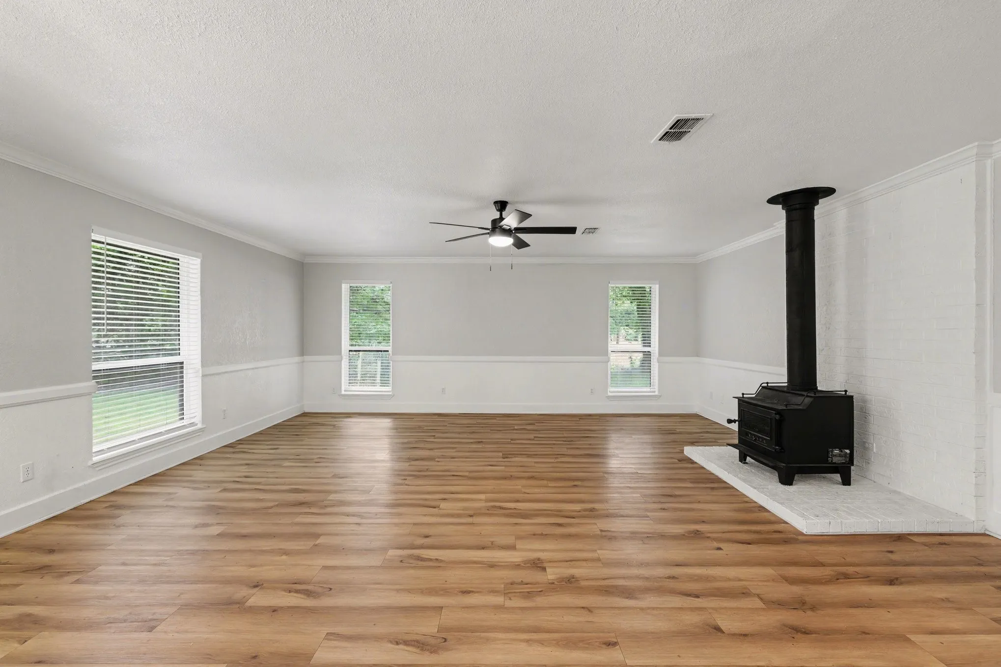 Living room shows wainscoting and brick-surround wood-burning stove