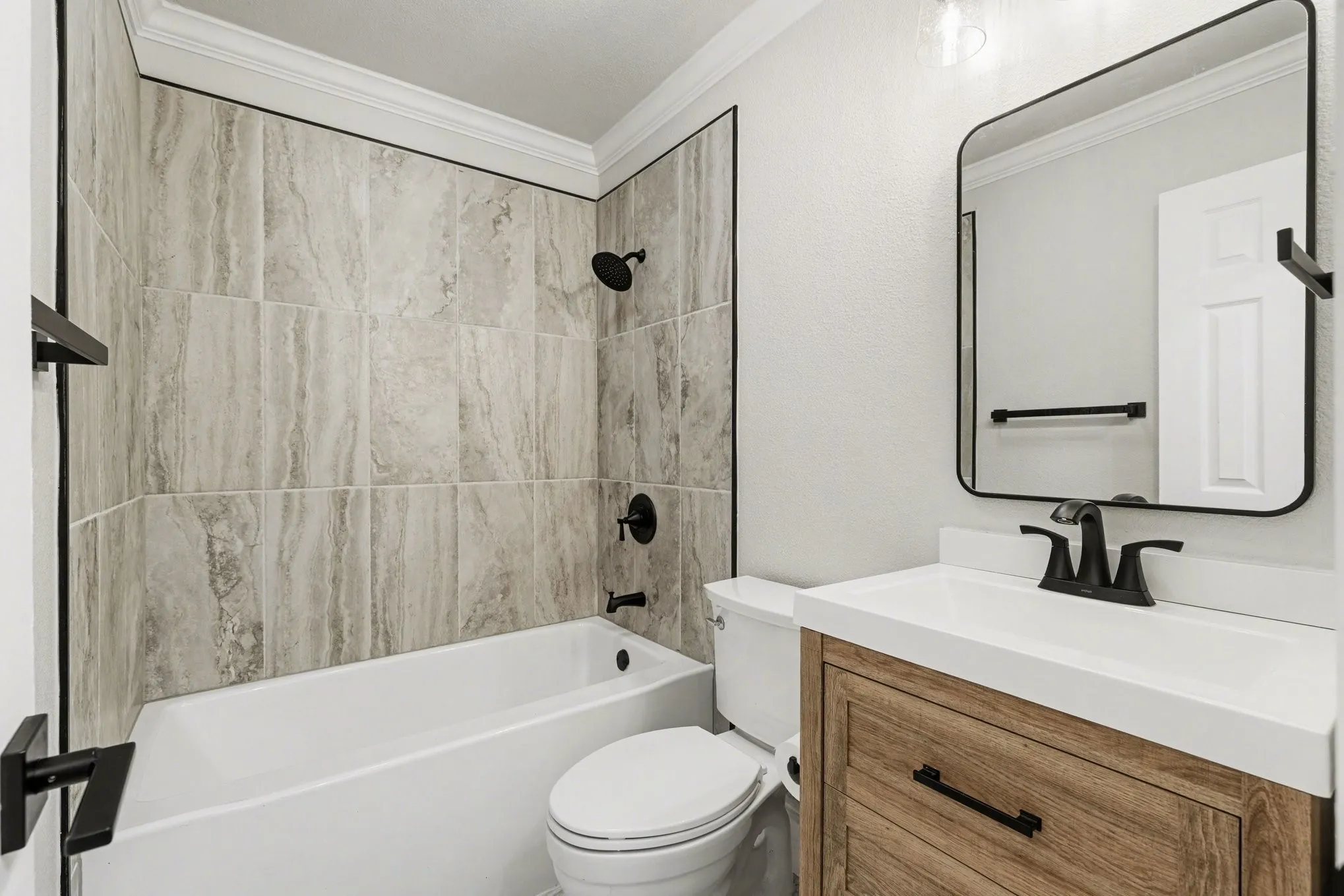 Bathroom with soaking tub, stacked tile surround, and matte black fixtures