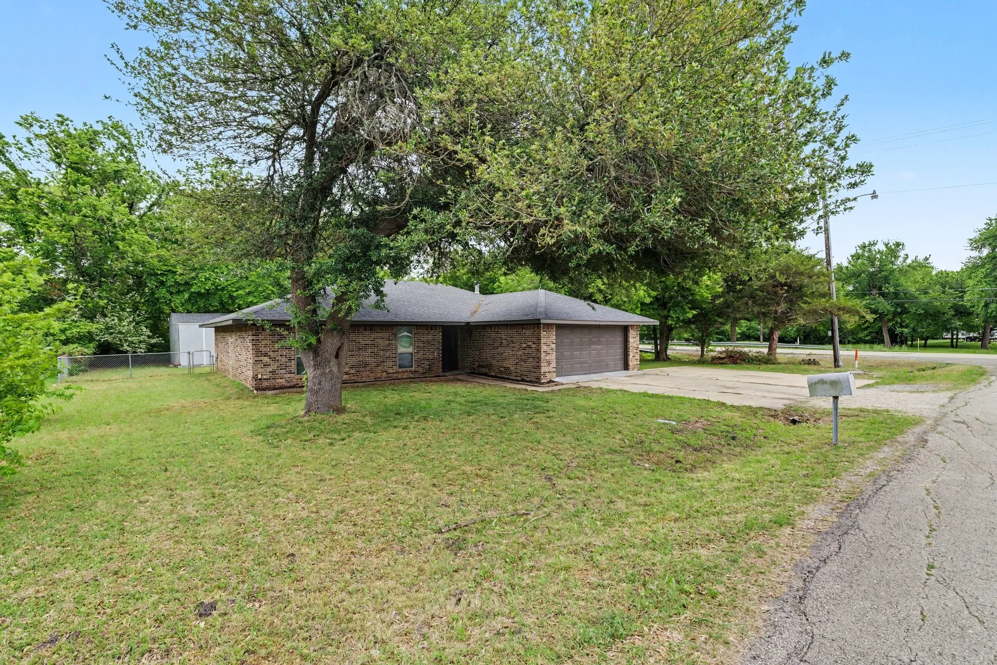 Classic brick front elevation with attached two-car garage and mature shade trees