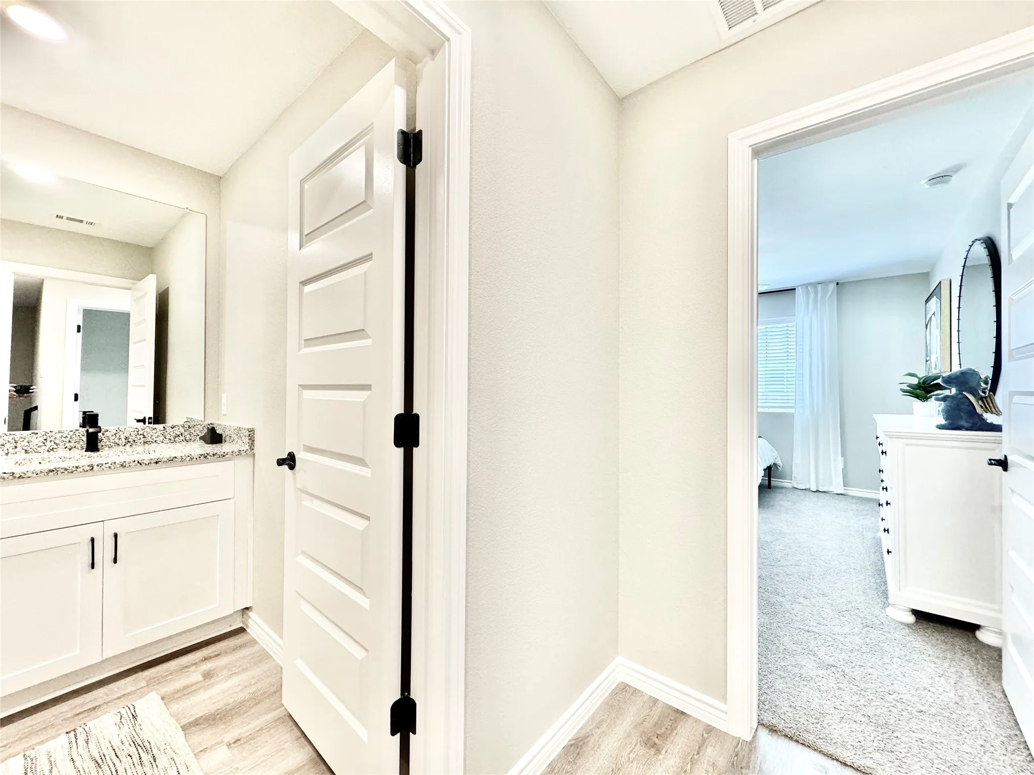Corridor with visible vents, light wood-style flooring, baseboards, and a sink