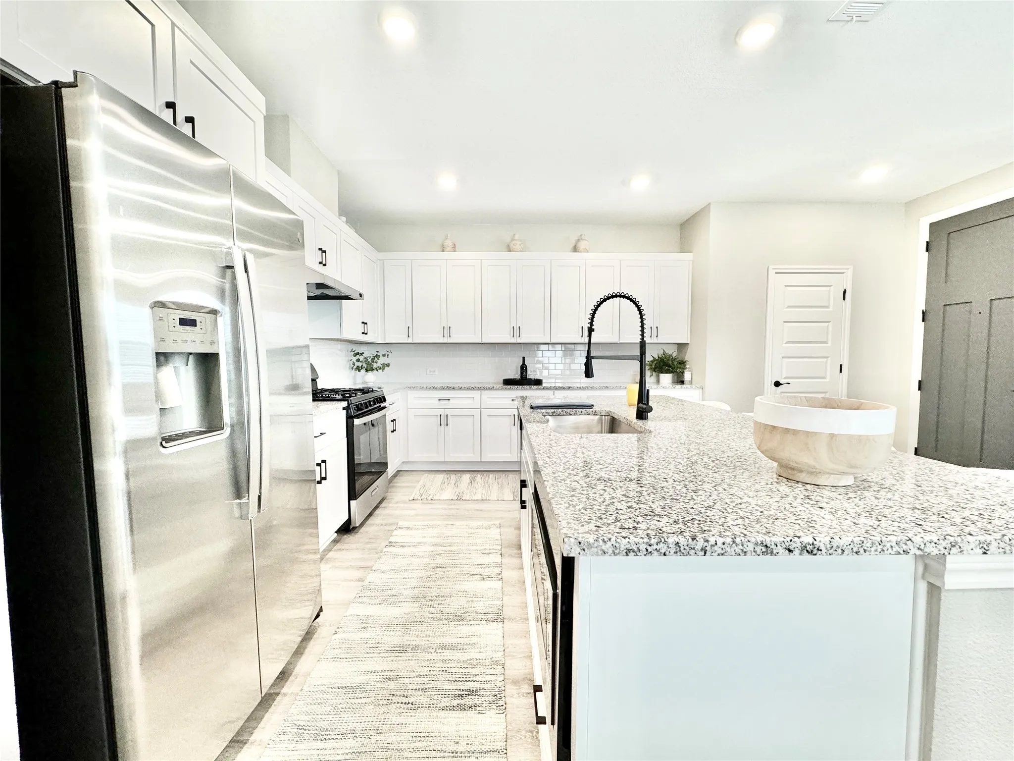 Kitchen featuring a sink, a kitchen island with sink, recessed lighting, gas stove, and stainless steel fridge with ice dispenser