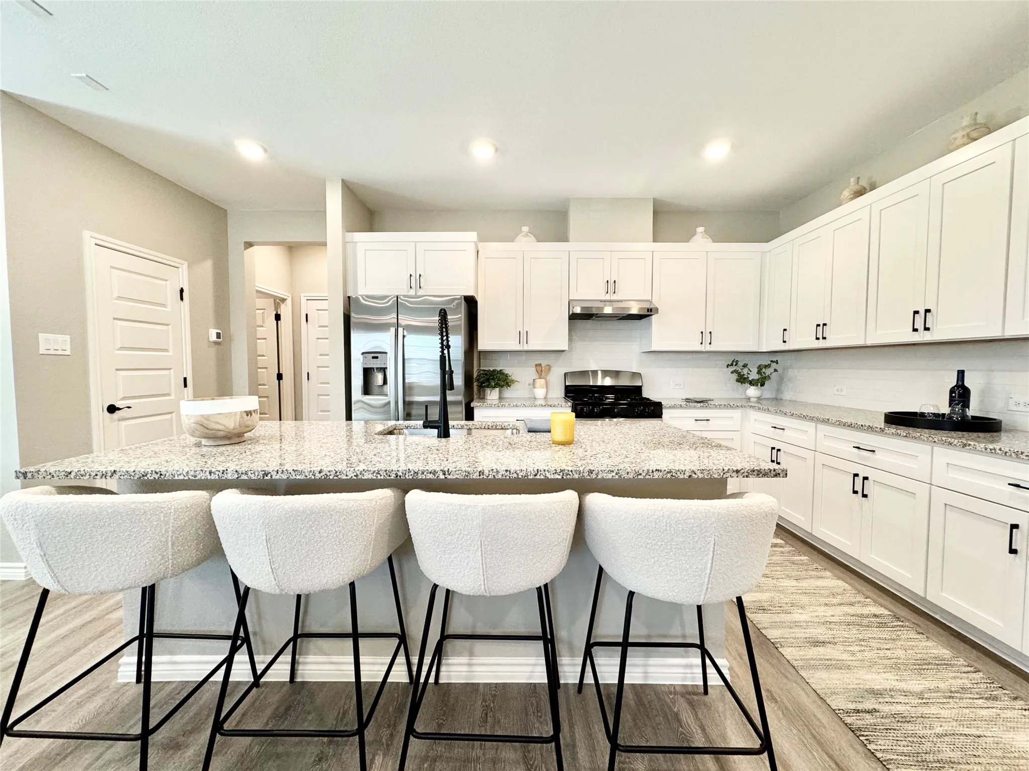 Kitchen with under cabinet range hood, gas range oven, a sink, stainless steel fridge, and light wood-style floors