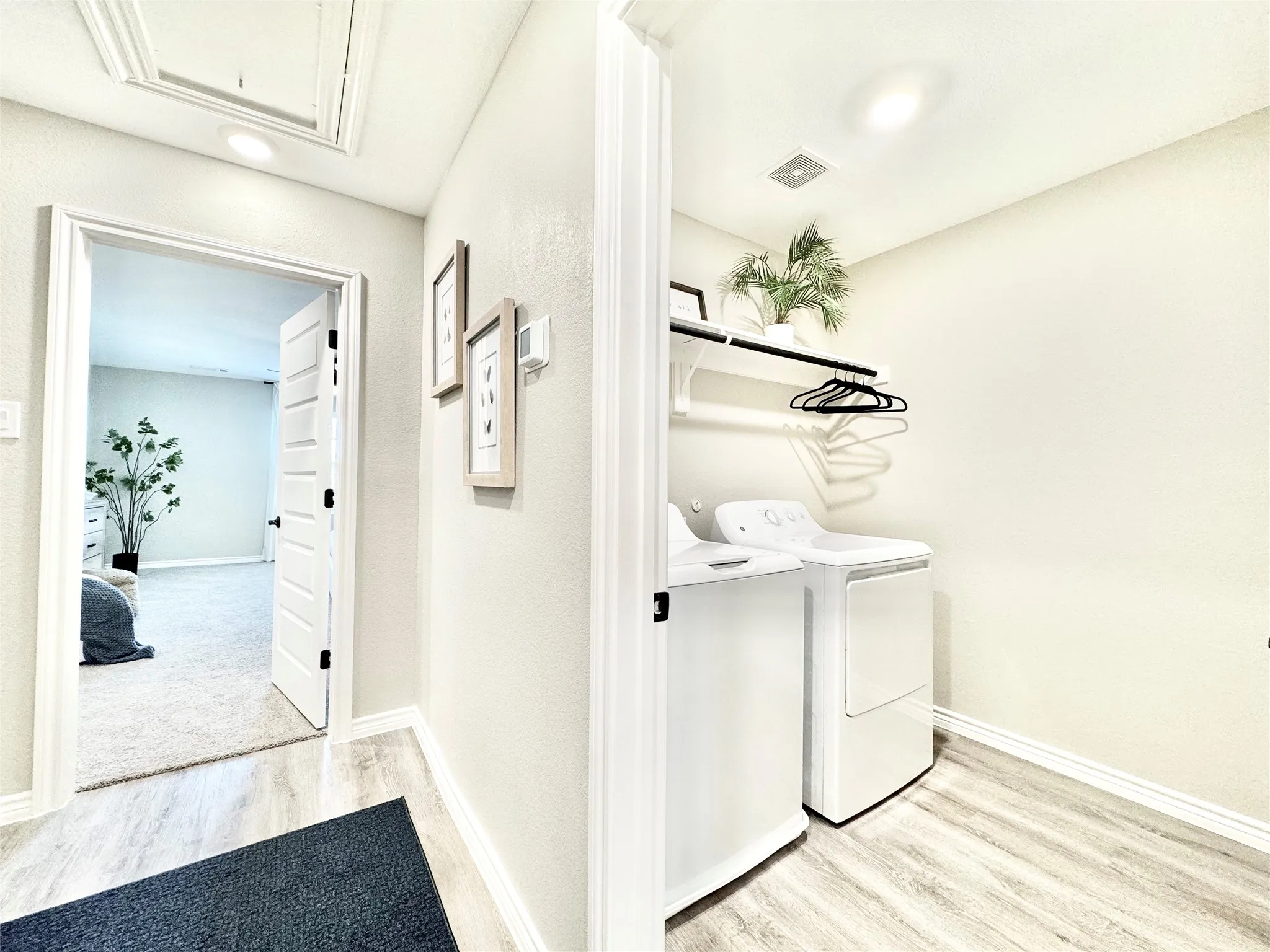 Laundry area featuring light wood-style flooring, baseboards, visible vents, washer and clothes dryer, and laundry area