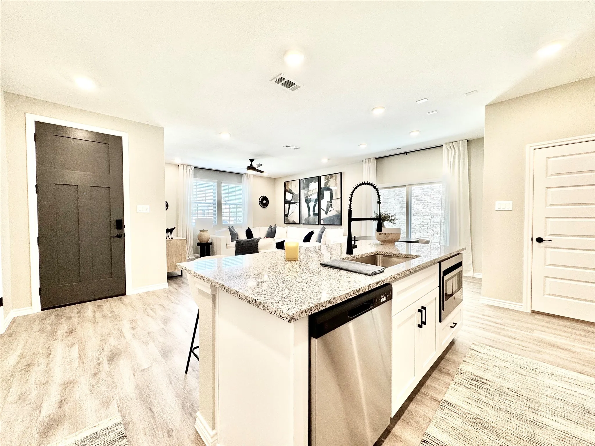 Kitchen with light stone countertops, light wood-style flooring, visible vents, a sink, and appliances with stainless steel finishes