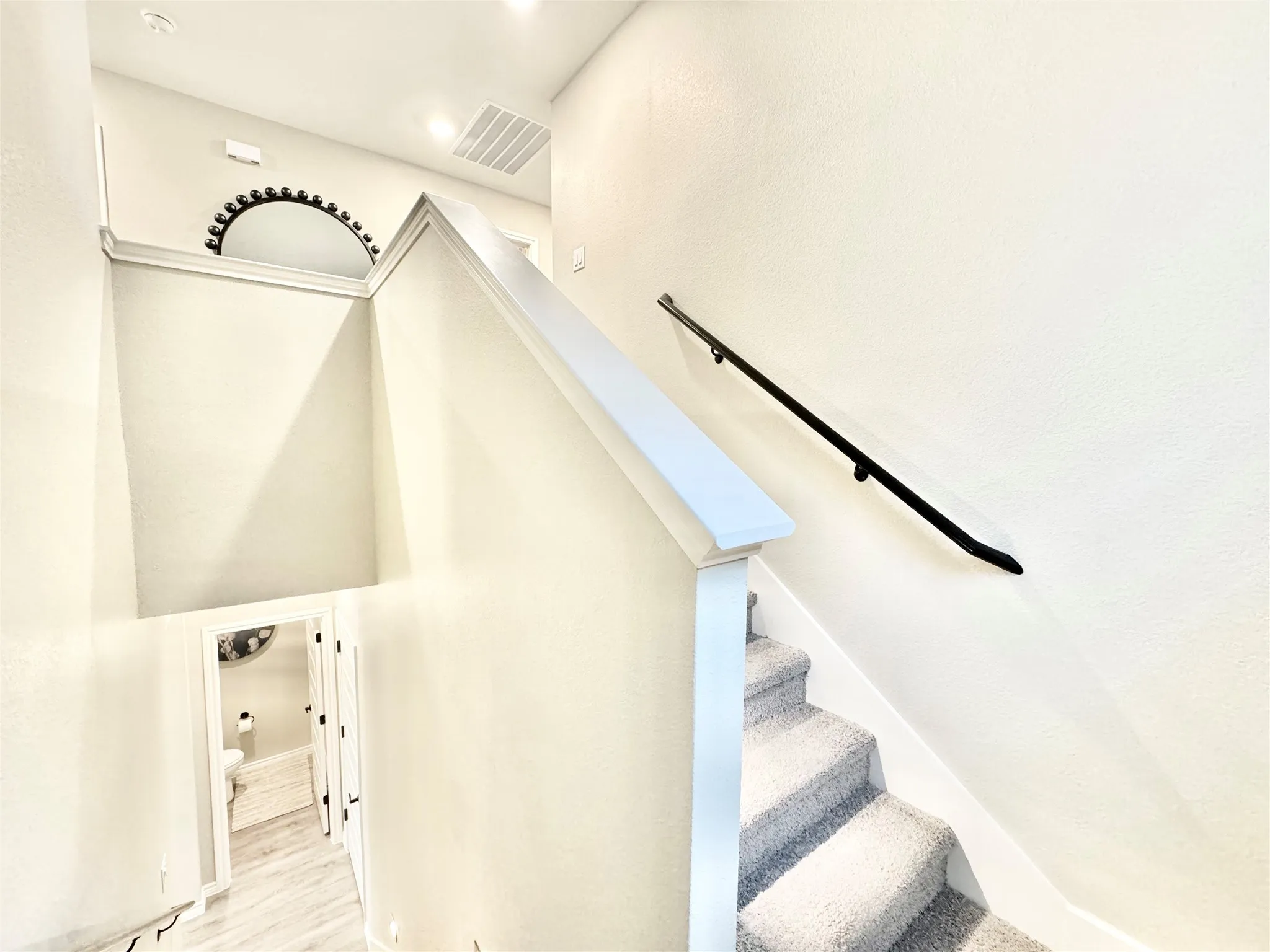 Staircase with recessed lighting, visible vents, and wood finished floors