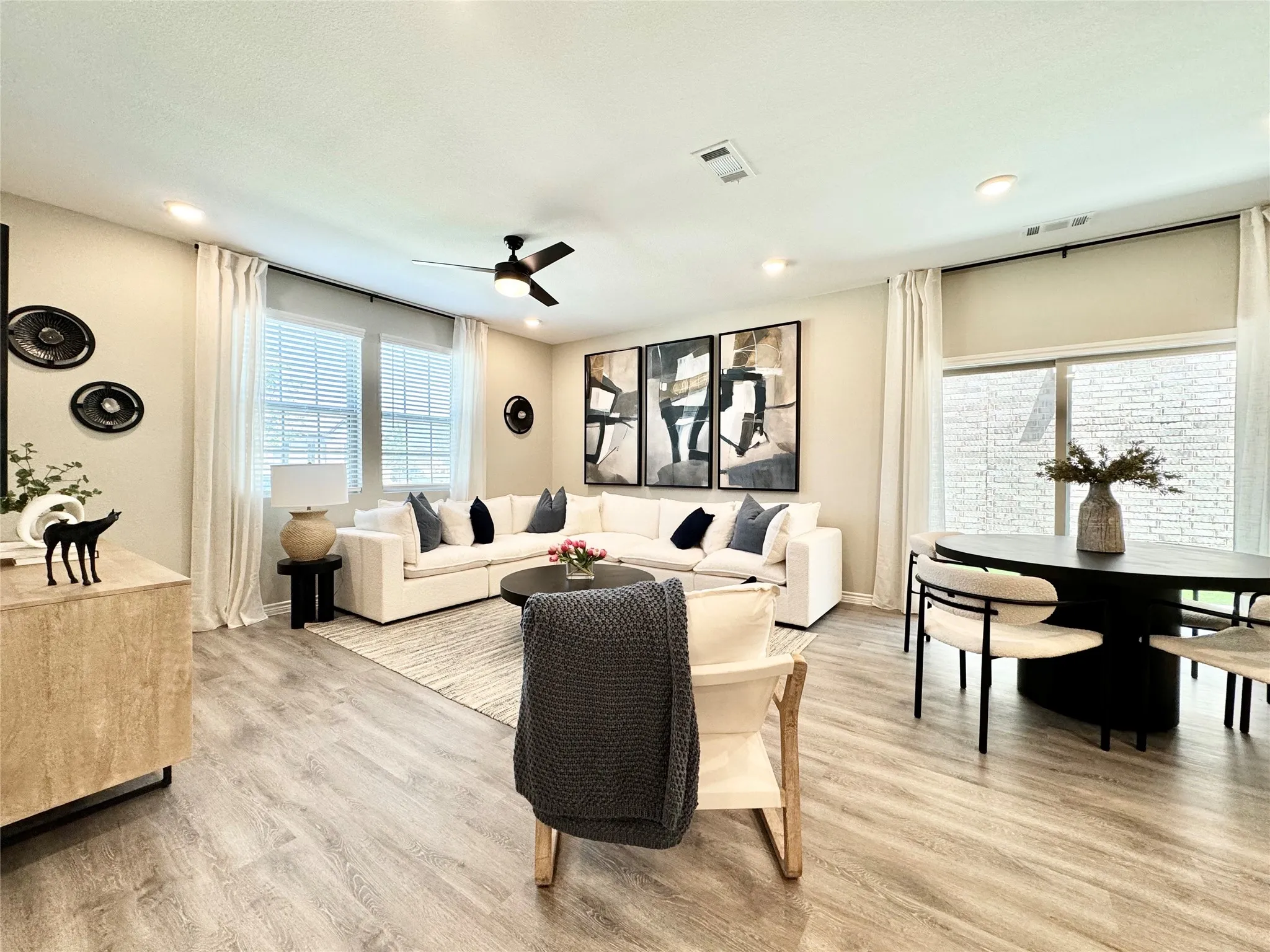 Living room featuring light wood finished floors, a ceiling fan, visible vents, and recessed lighting