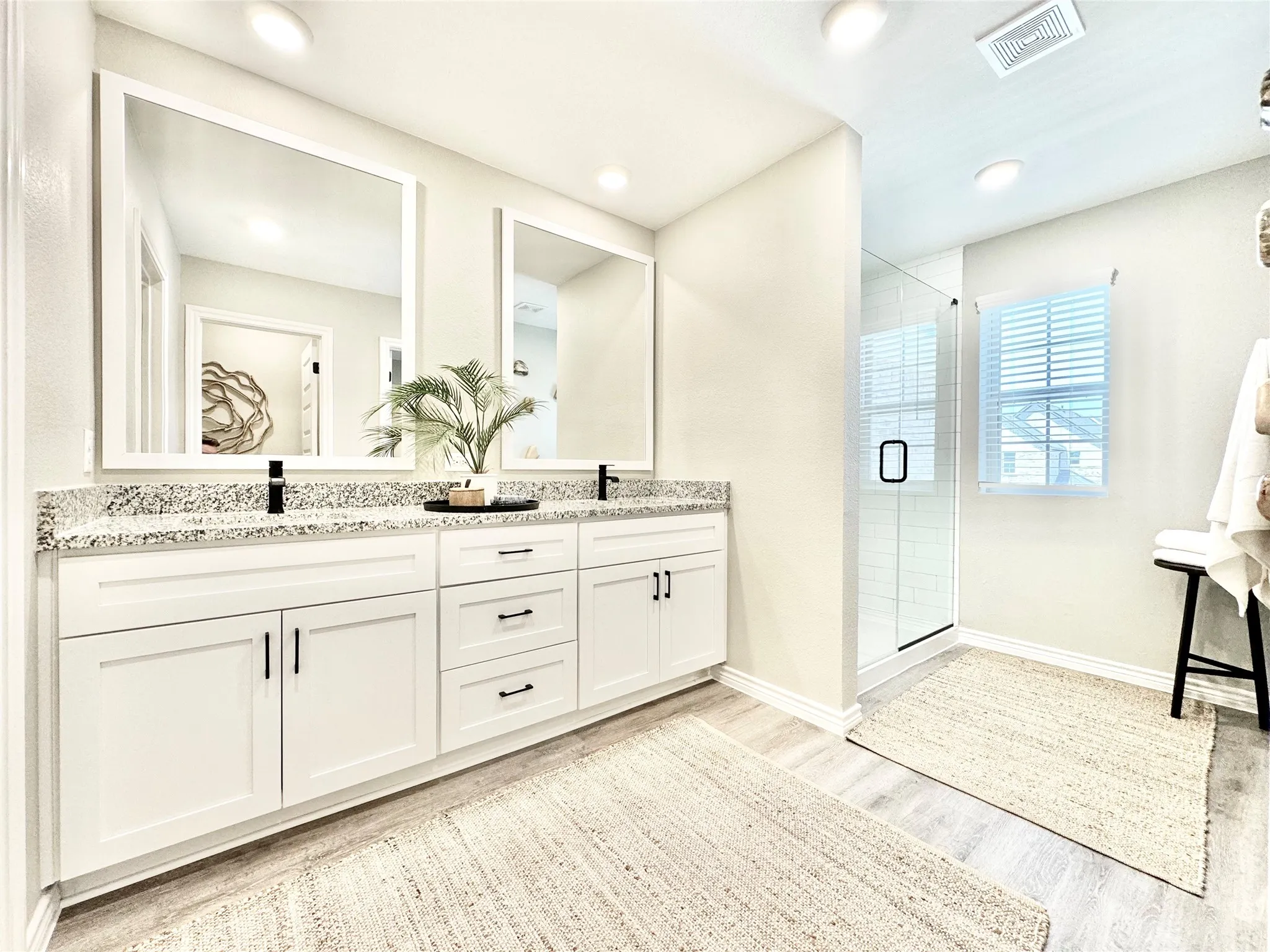 Full bath with double vanity, wood finished floors, a sink, visible vents, and a shower stall