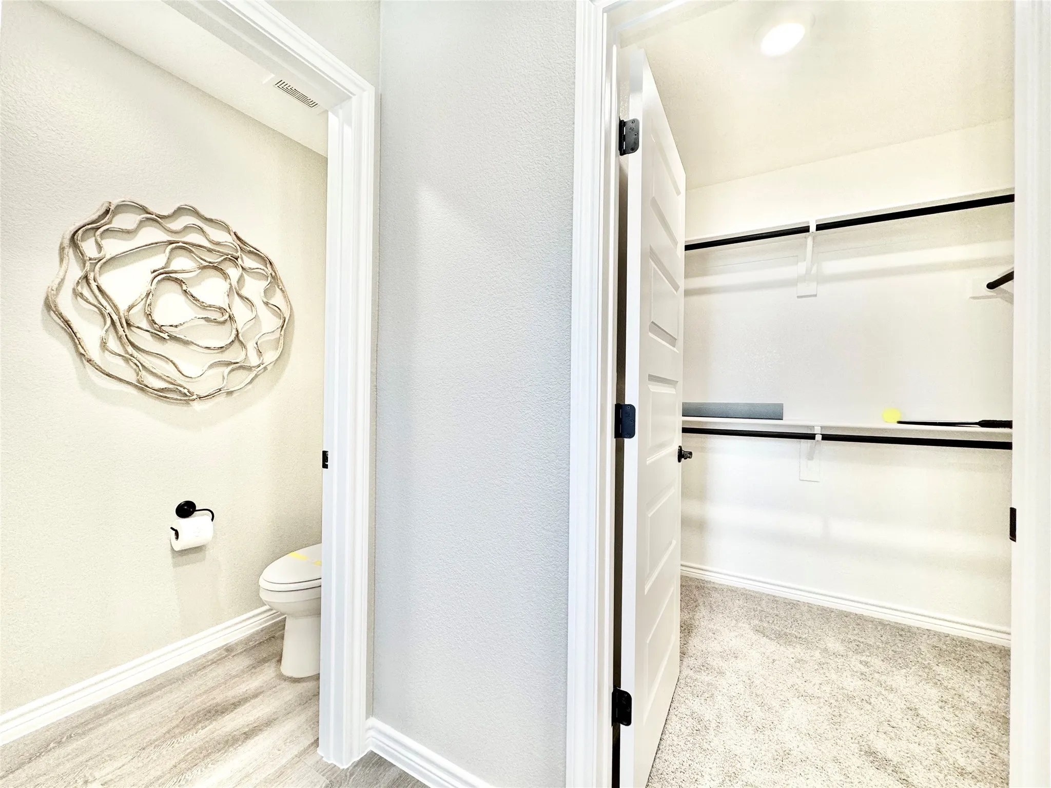 Bathroom with toilet, visible vents, baseboards, and a walk in closet