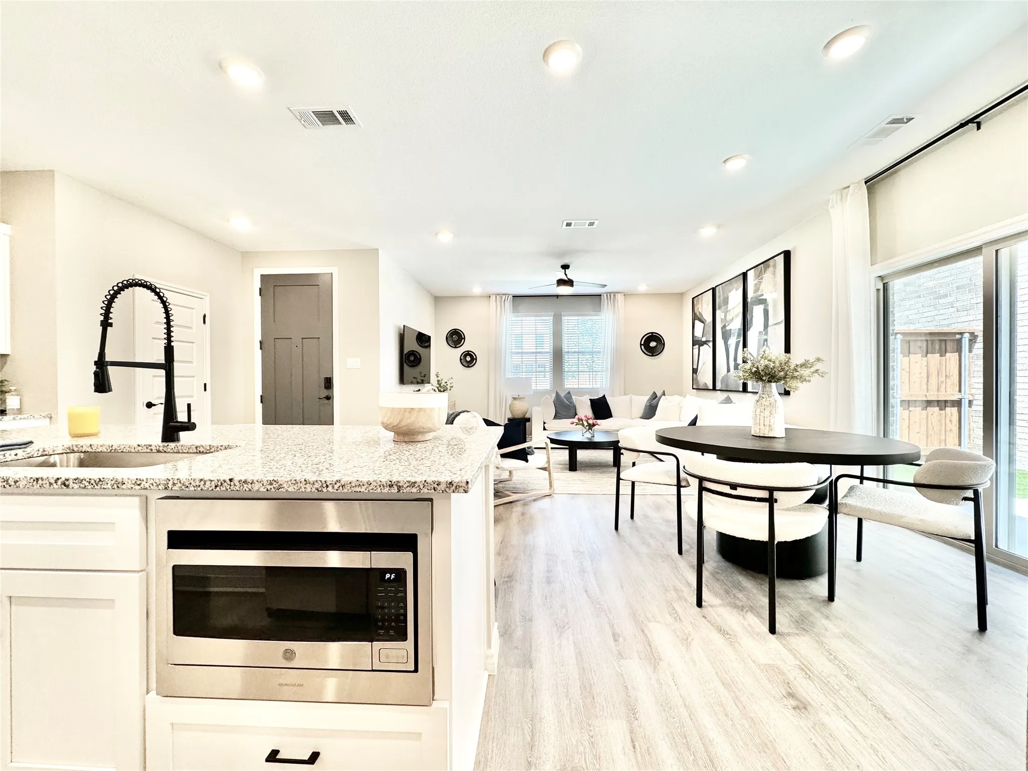 Kitchen with light stone countertops, a sink, ceiling fan, and stainless steel microwave