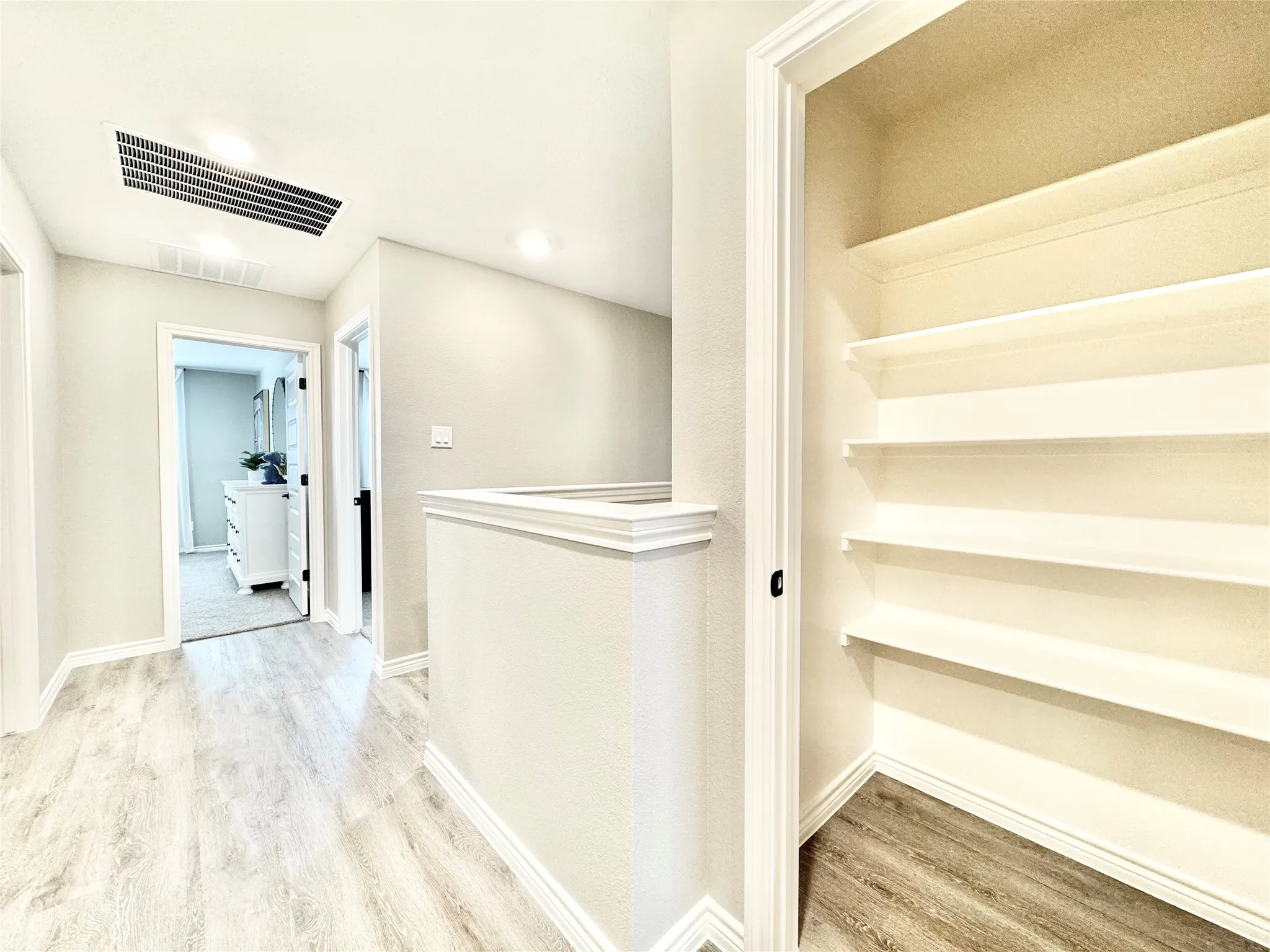 Hallway featuring an upstairs landing, baseboards, visible vents, and wood finished floors