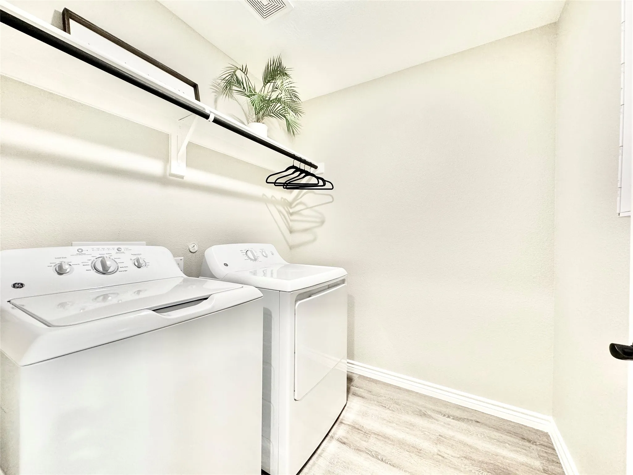 Laundry room featuring independent washer and dryer, laundry area, light wood-type flooring, visible vents, and baseboards