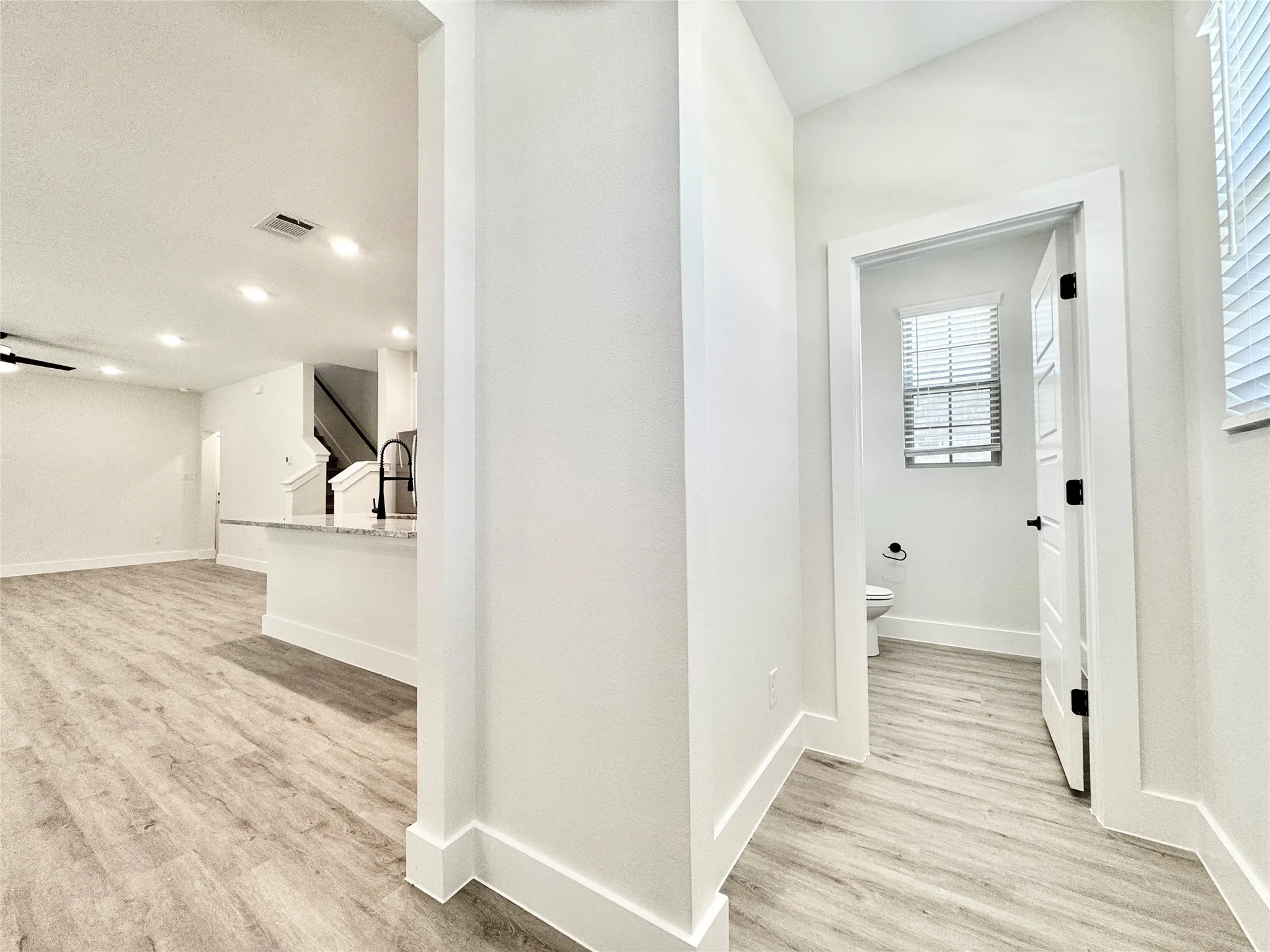 Hall with light wood finished floors, baseboards, and recessed lighting