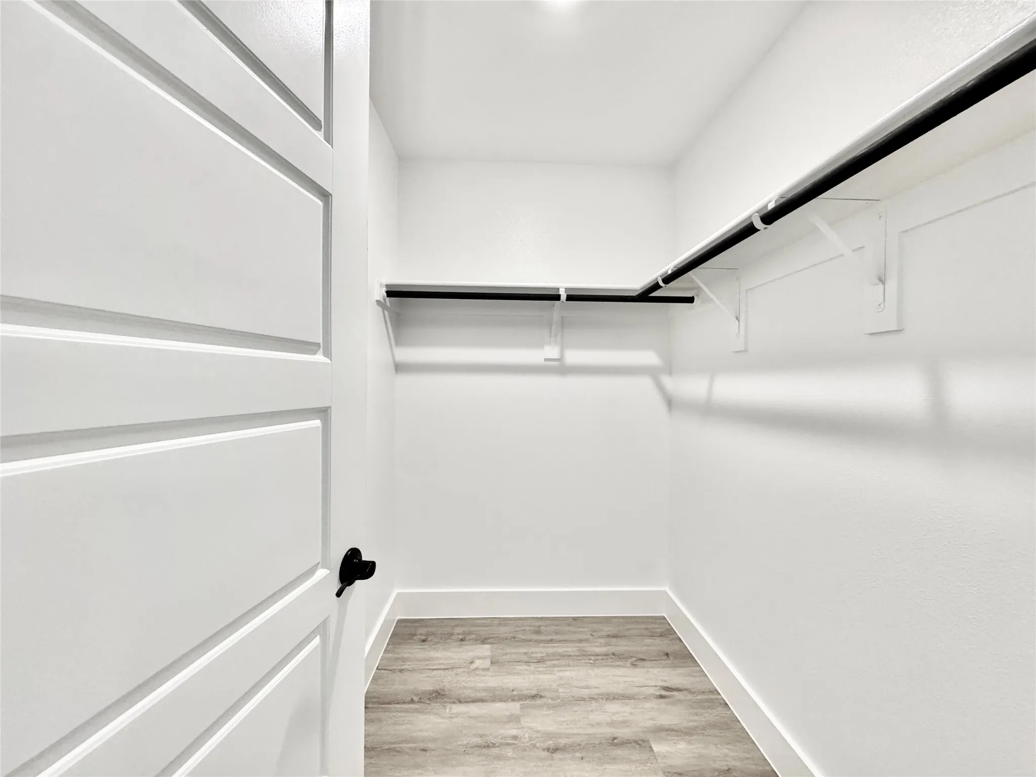 Walk in closet with light wood-style floors