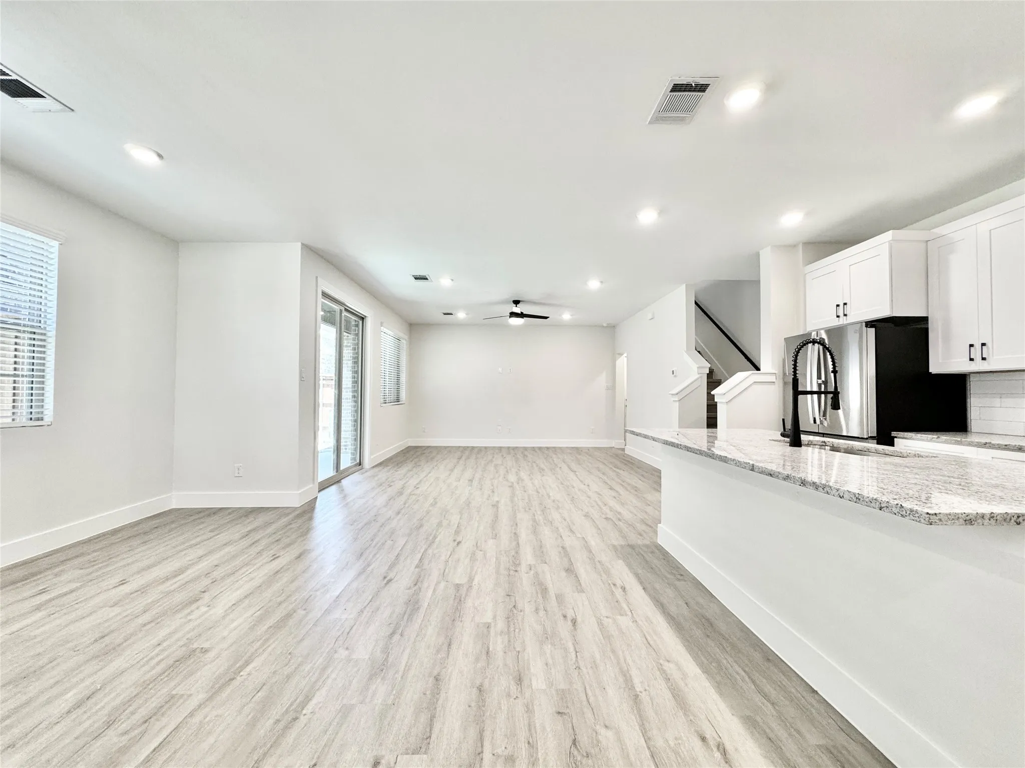 Unfurnished living room with recessed lighting, light wood finished floors, stairs, a ceiling fan, and baseboards