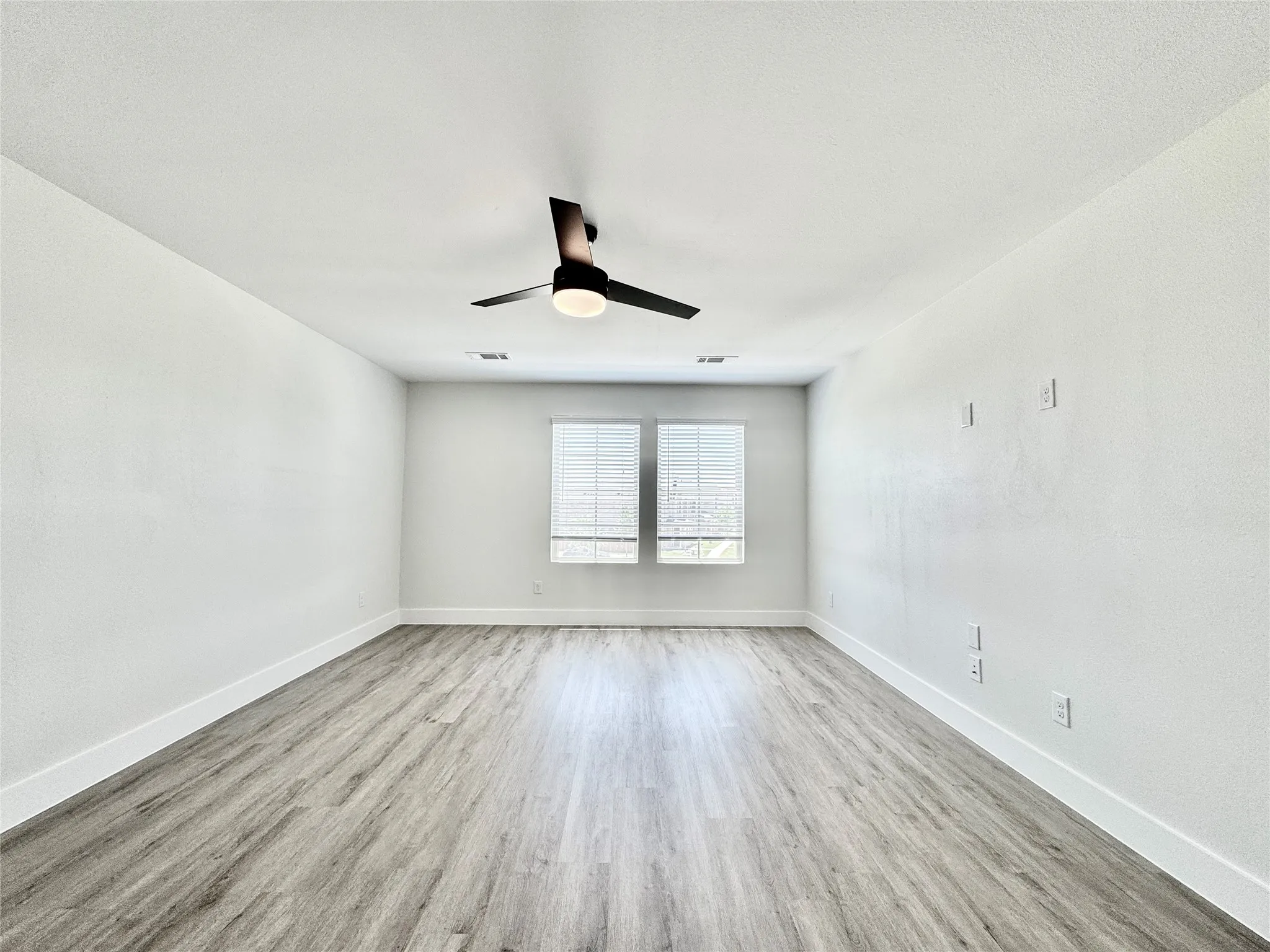Empty room featuring wood finished floors, a ceiling fan, and baseboards