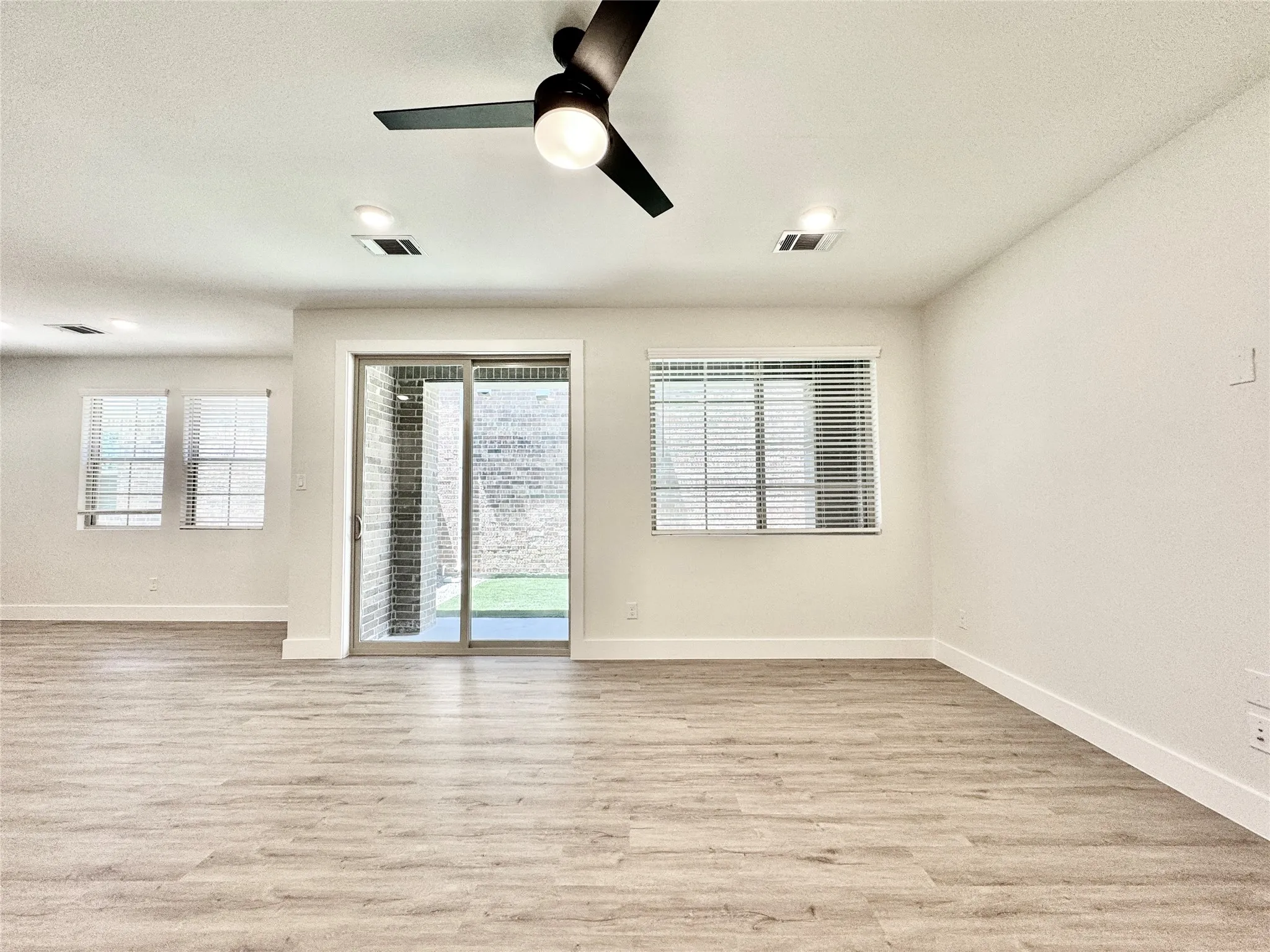 Spare room with light wood-style floors, baseboards, and ceiling fan