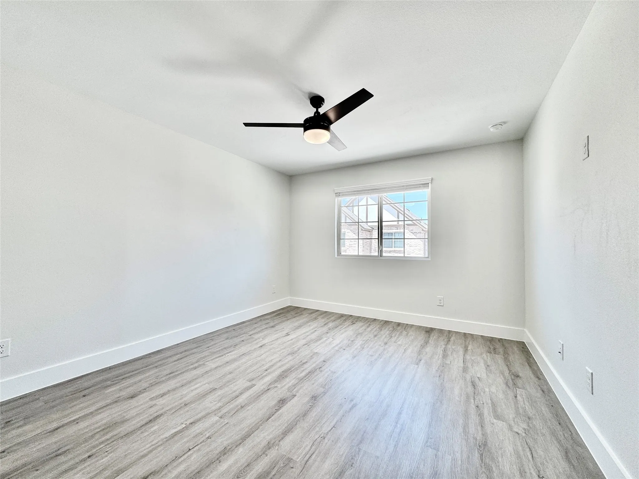 Spare room featuring wood finished floors, baseboards, and a ceiling fan