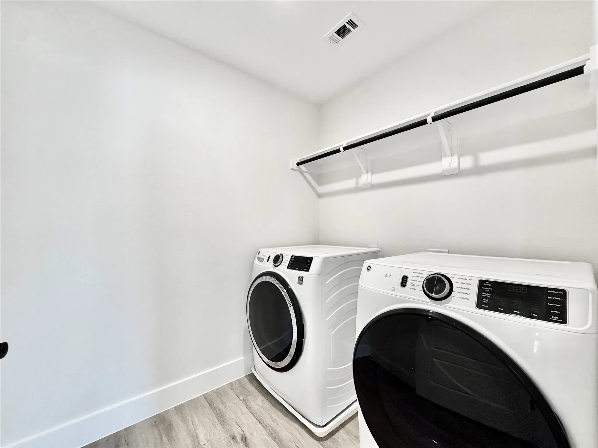 Laundry room featuring washer and clothes dryer, light wood-style flooring, and baseboards