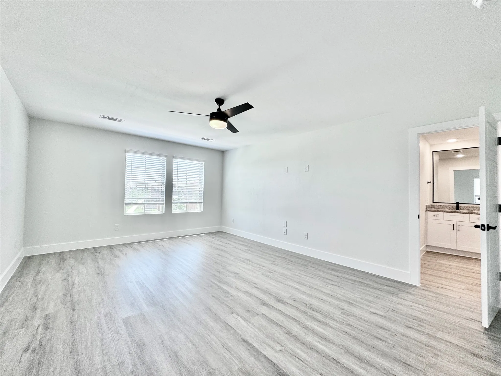 Empty room featuring light wood-style floors, a ceiling fan, and baseboards