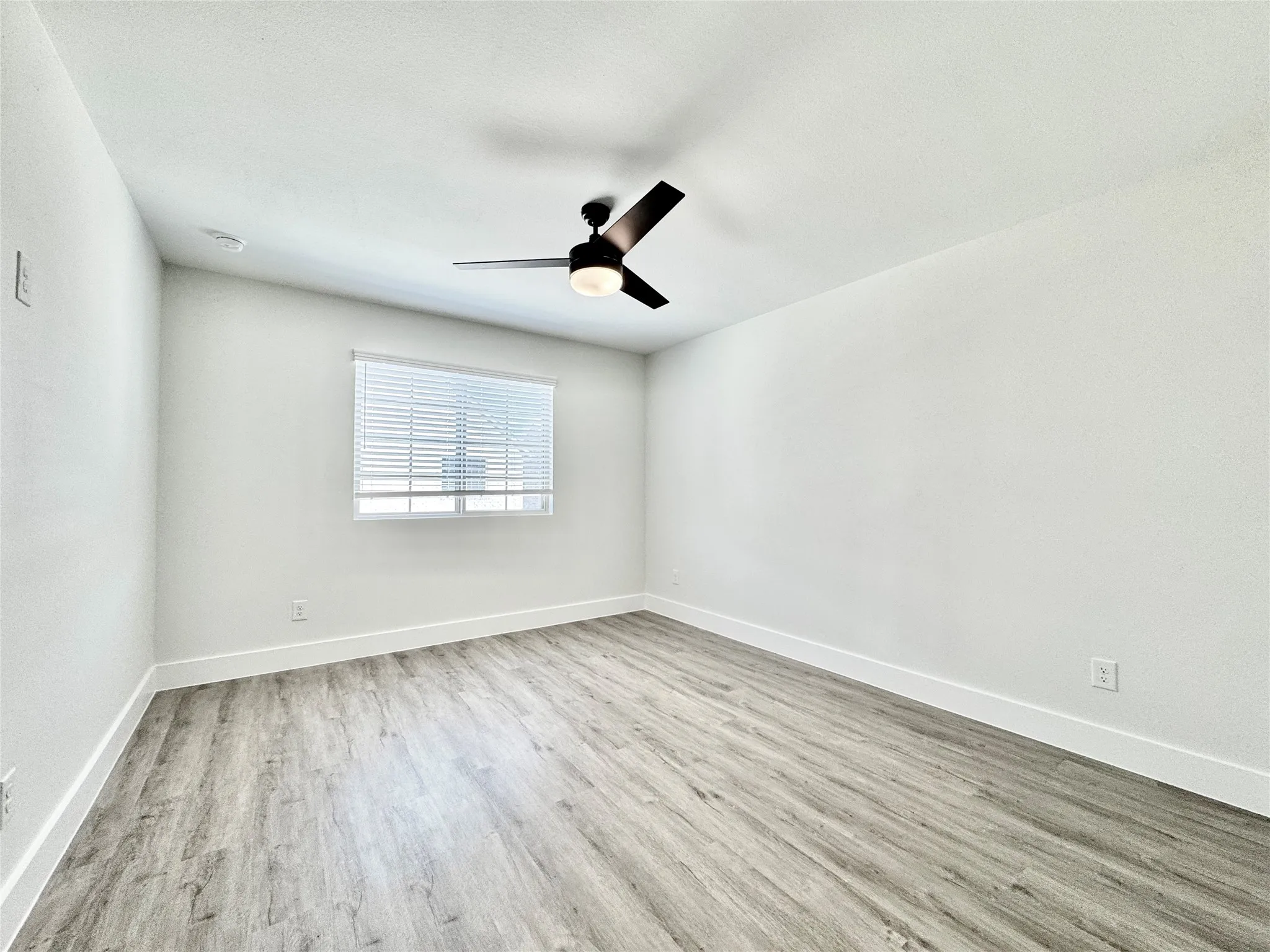 Spare room featuring wood finished floors, ceiling fan, and baseboards