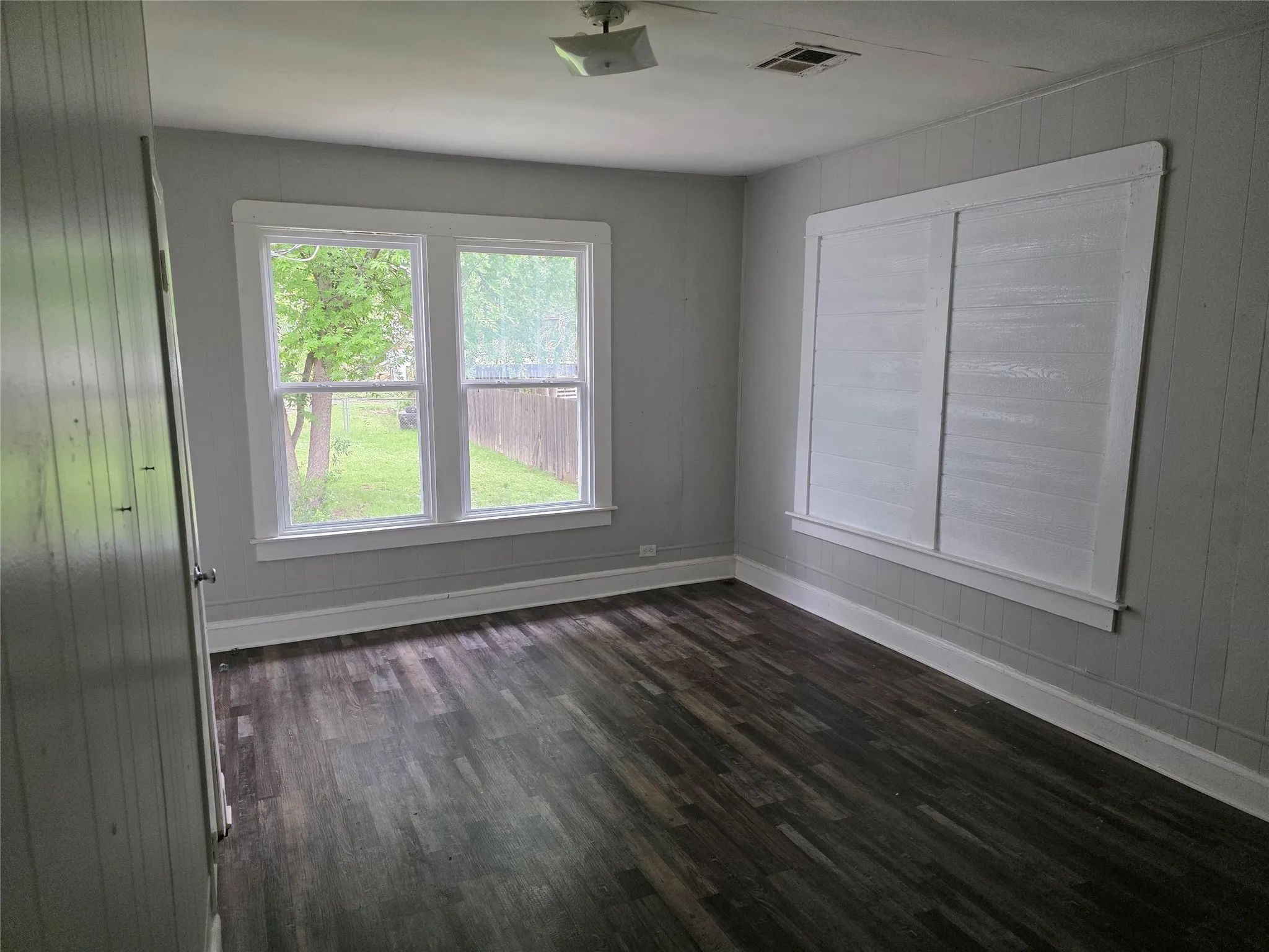 This room features dark-toned plank flooring, light gray walls, and white trim