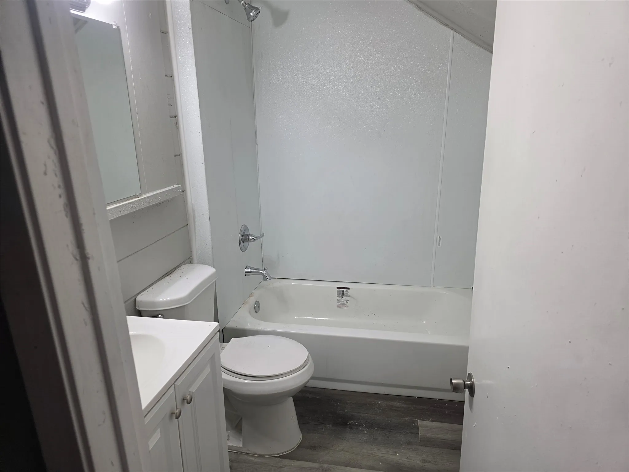 The bathroom features a white vanity with a rectangular sink, a toilet, and a white bathtub with a shower