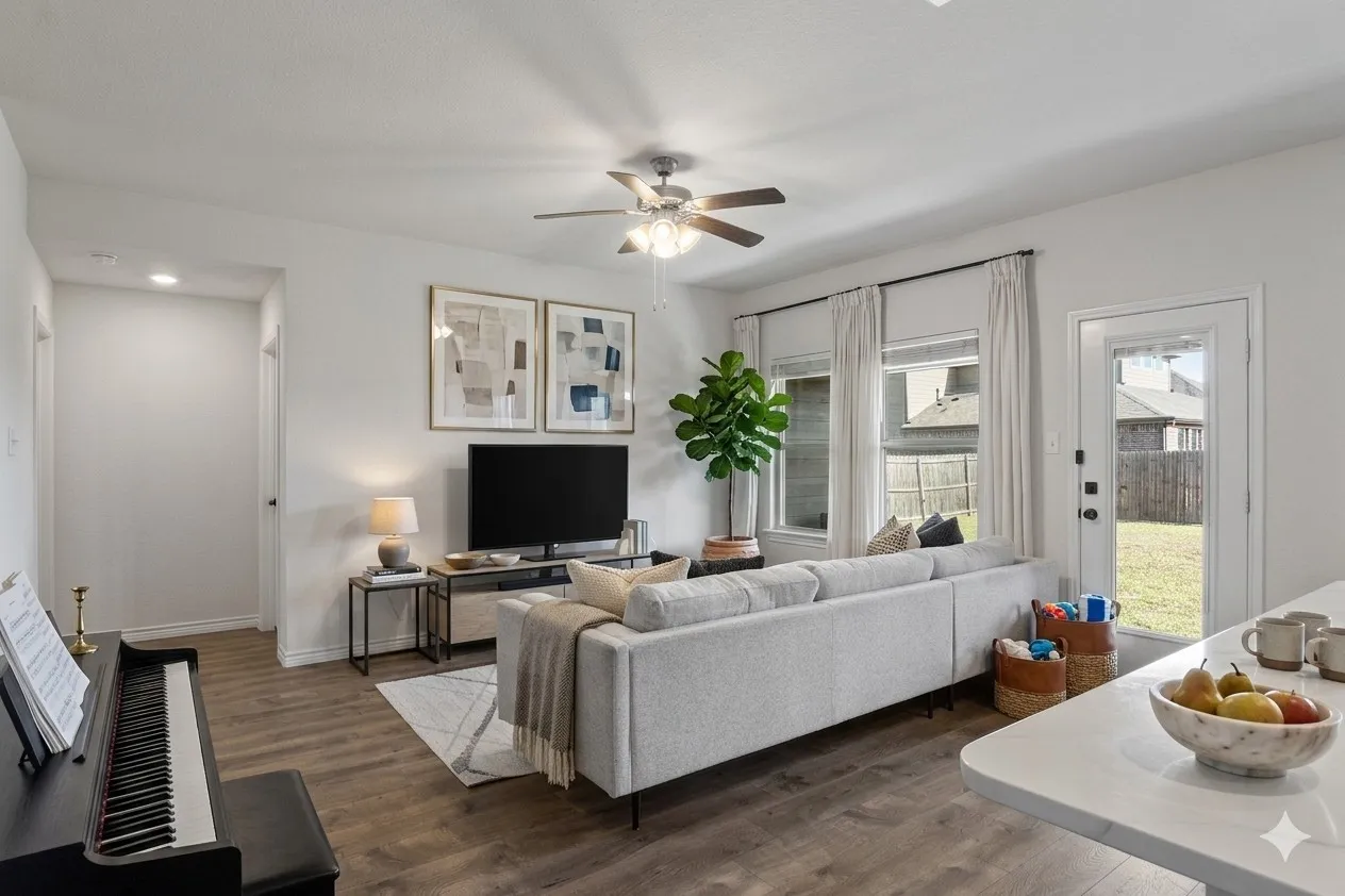 The living area features wood-look flooring, light-toned walls, and a ceiling fan