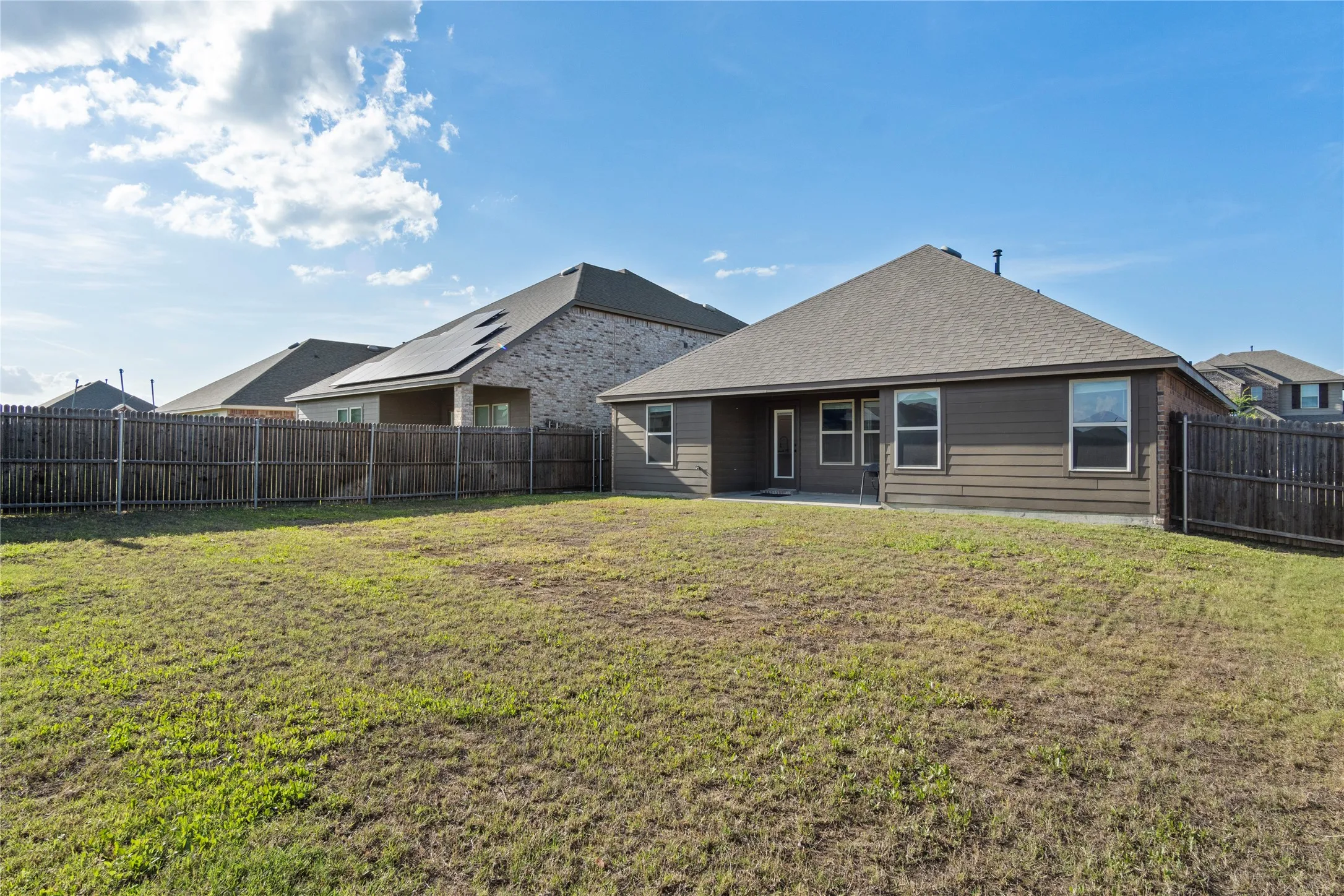 The property features an extensive yard with a lawn, a wooden fence, and a patio area