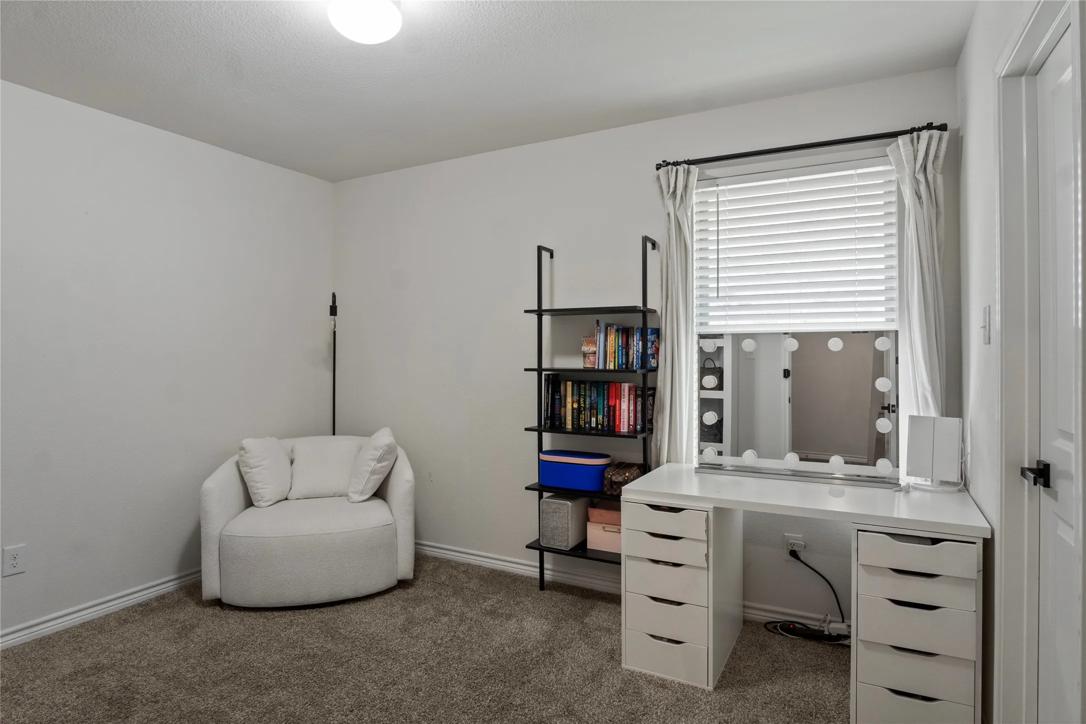 This room features neutral-toned walls, a window with blinds, and carpeted flooring