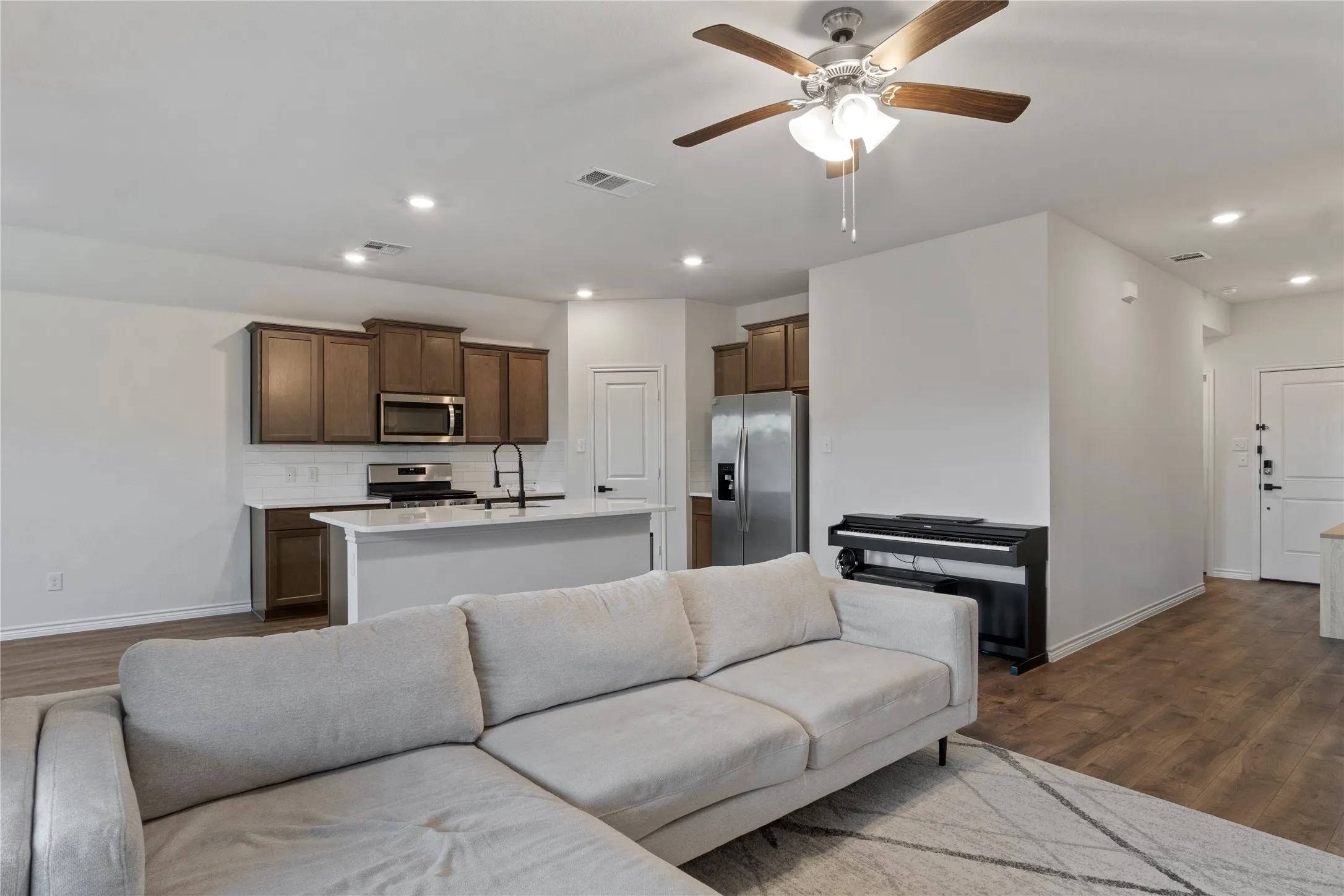 The open concept living area features recessed lighting, a ceiling fan, and hardwood flooring