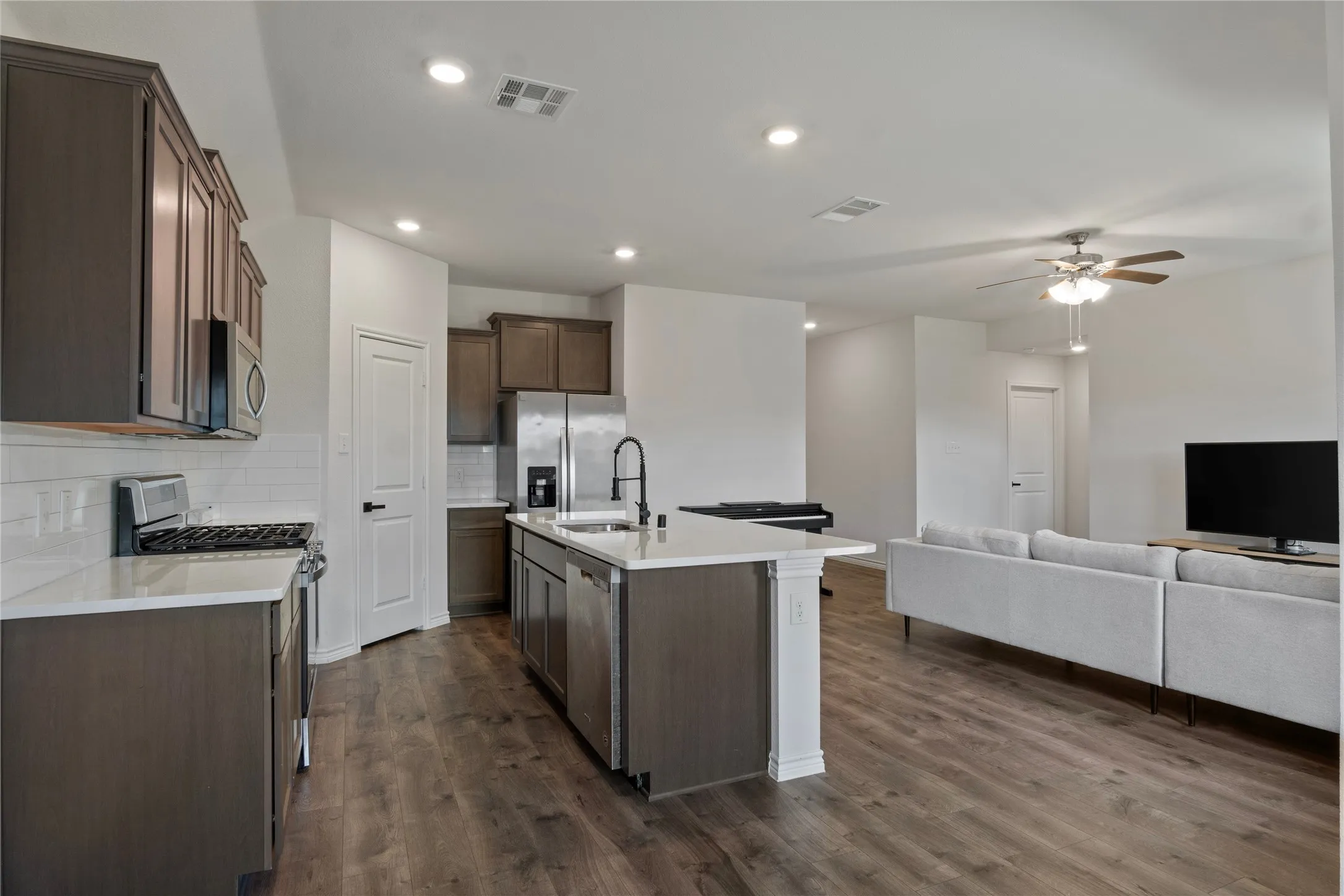 The open-concept living area features wood-look flooring, recessed lighting, and a ceiling fan