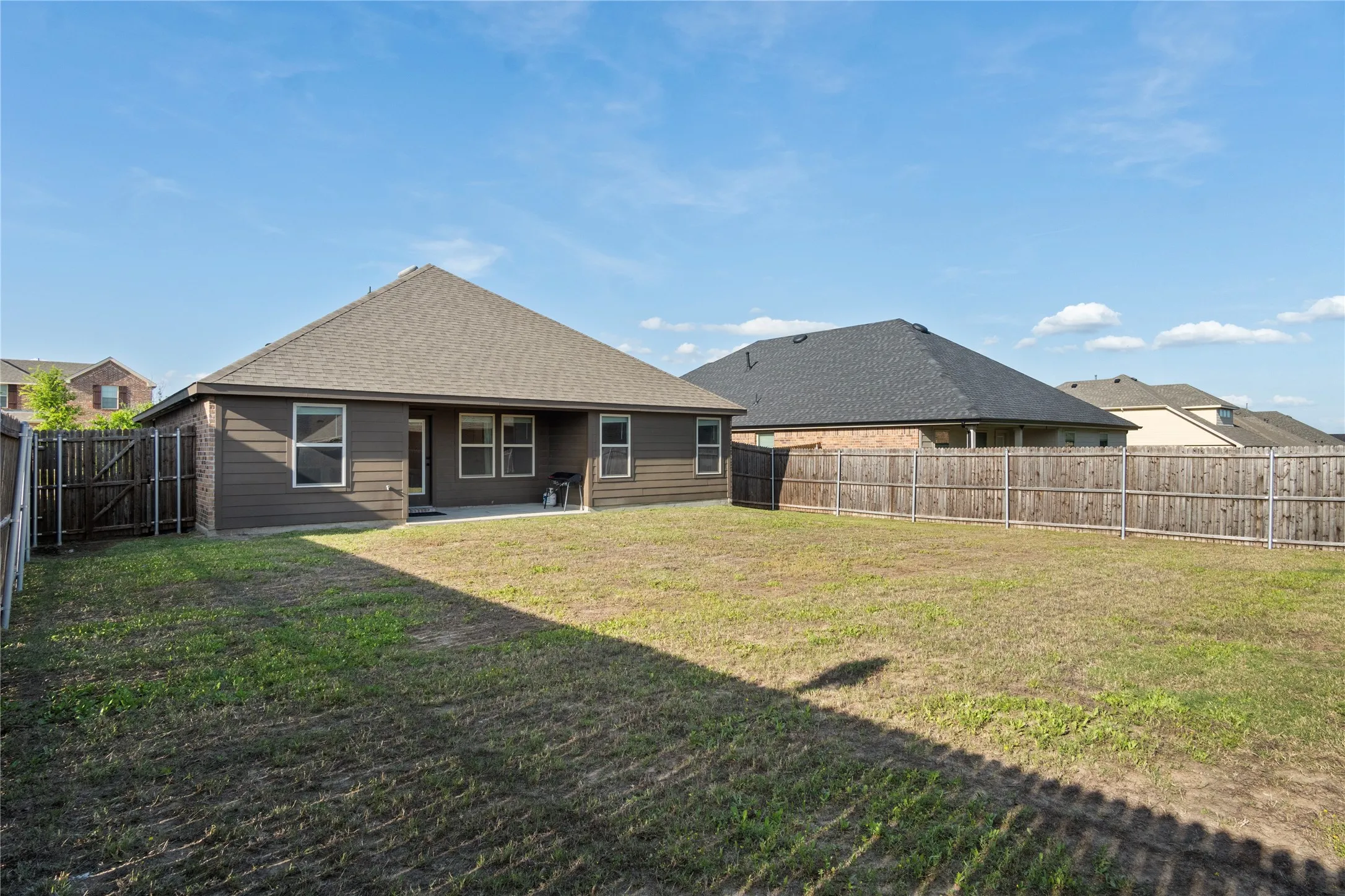 The property features a spacious backyard with a lawn and a privacy fence