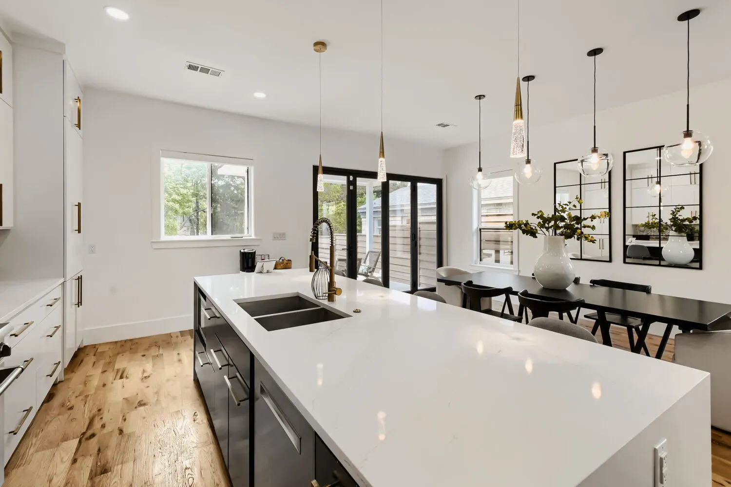 Kitchen with two tone color scheme, light stone counters, light wood finished floors, and a spacious island