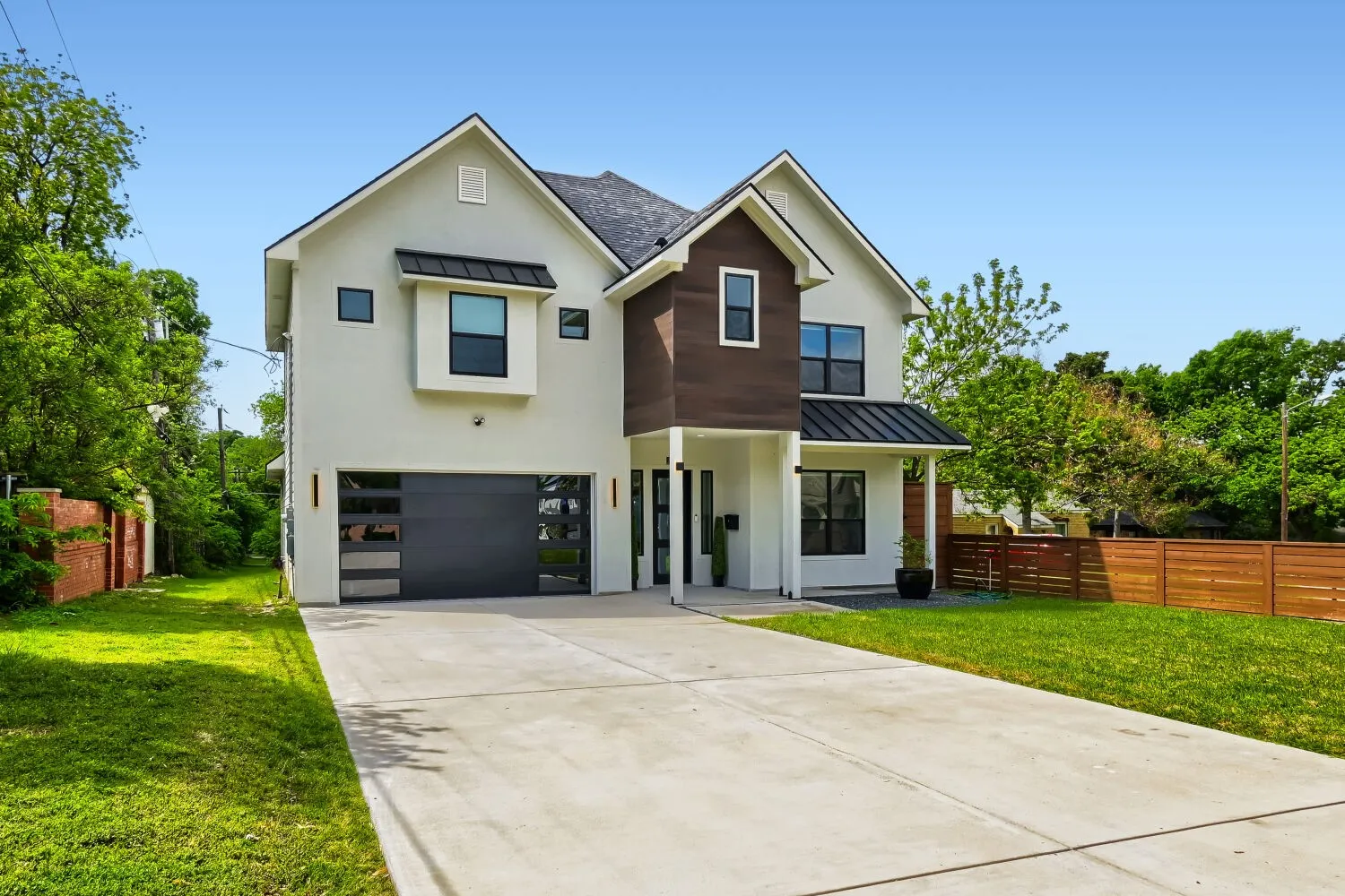 View of front facade featuring a standing seam roof, driveway, a garage, and stucco siding
