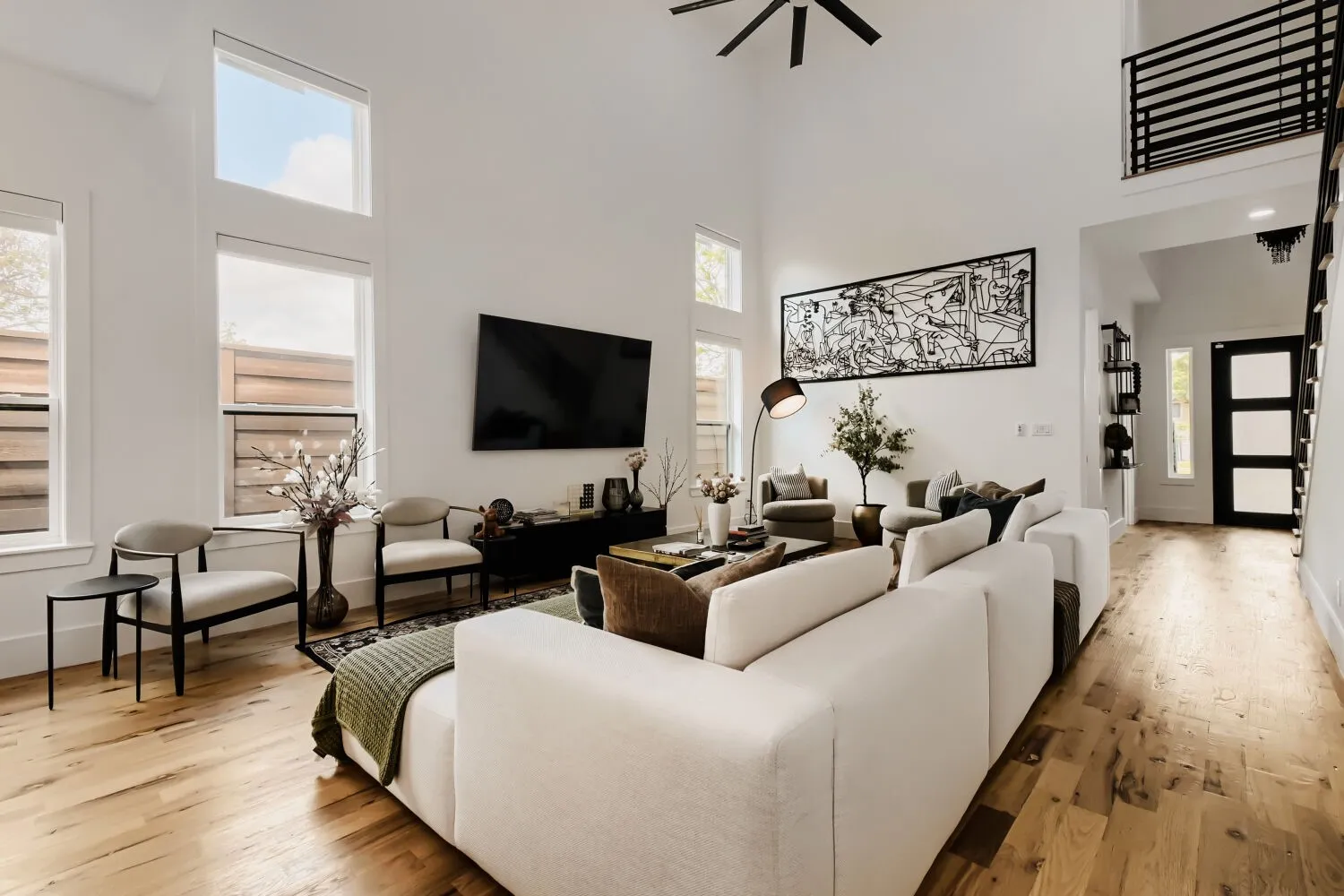 Living room featuring light wood-style floors, a ceiling fan, and a high ceiling