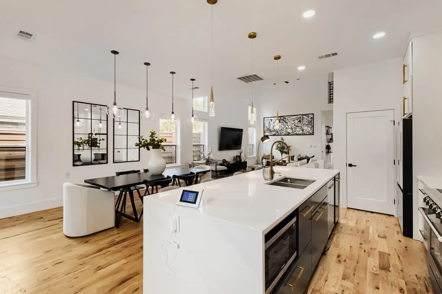 Dual tone kitchen with a kitchen island with sink, open floor plan, pendant lighting, light stone counters, and two tone cabinets