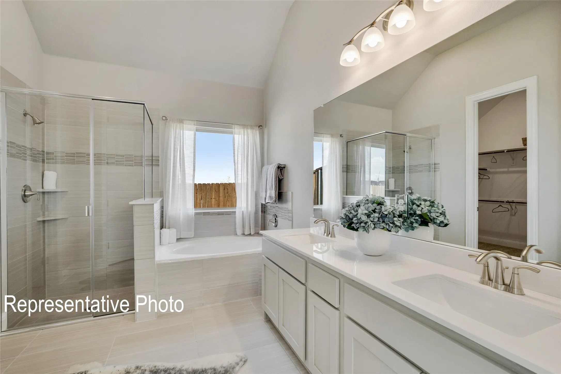 The bathroom features a glass-enclosed shower, a separate bathtub beneath a window, and a double vanity with two sinks