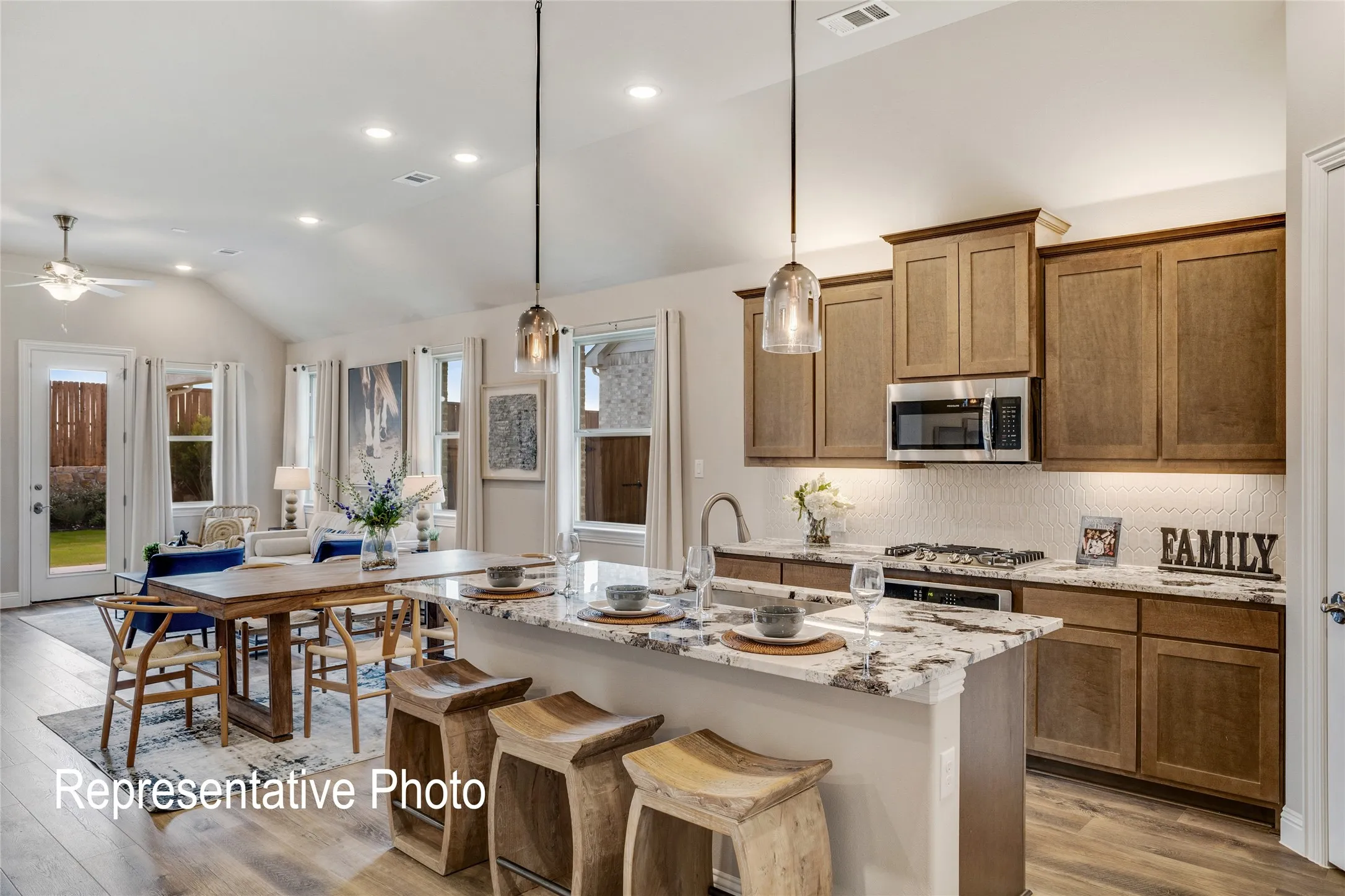 The open-concept living area features a kitchen with light wood cabinetry, a large kitchen island with a granite countertop, and stainless steel appliances