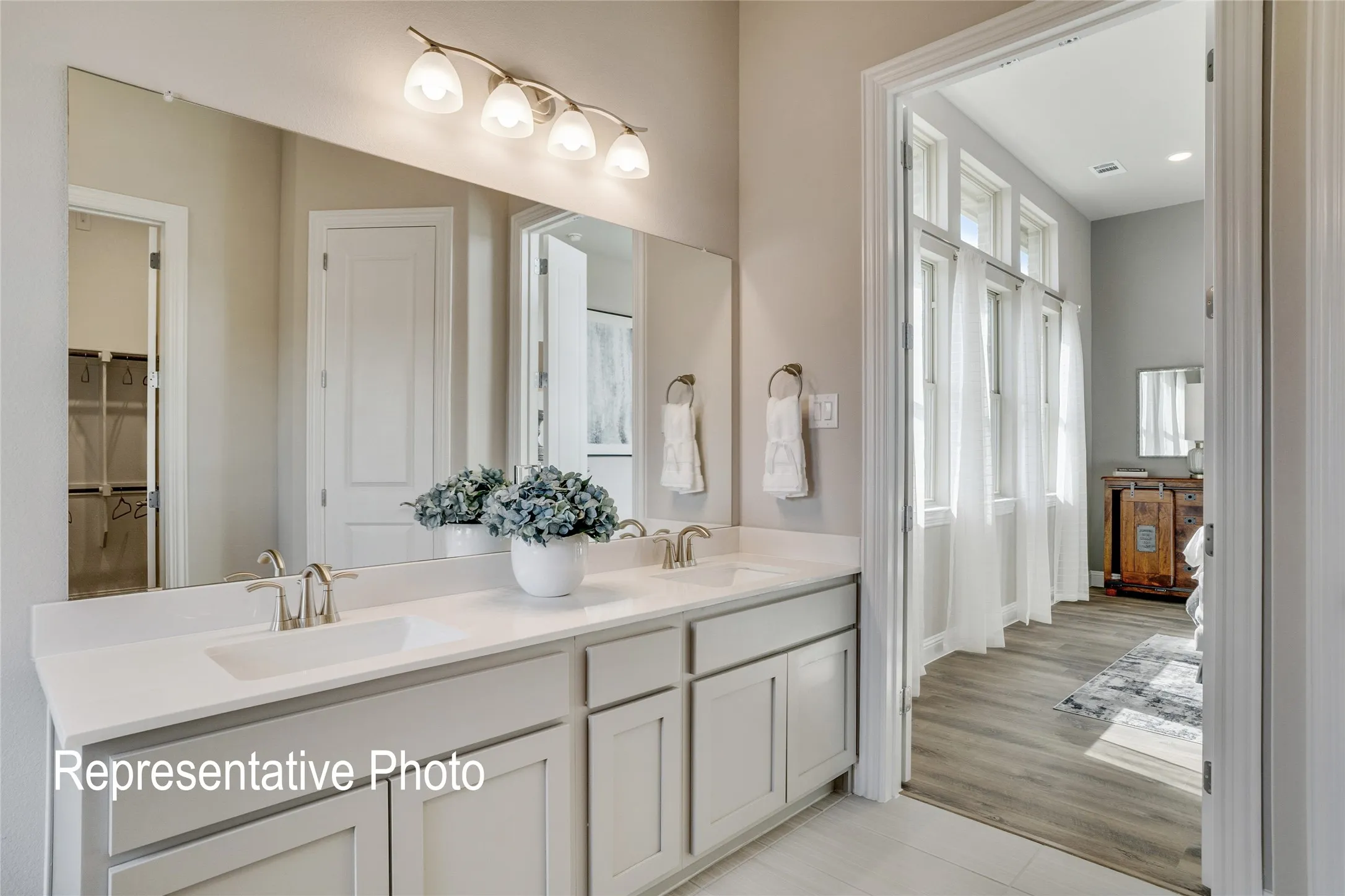 Bathroom featuring a dual sink vanity with light-colored cabinetry and a large mirror