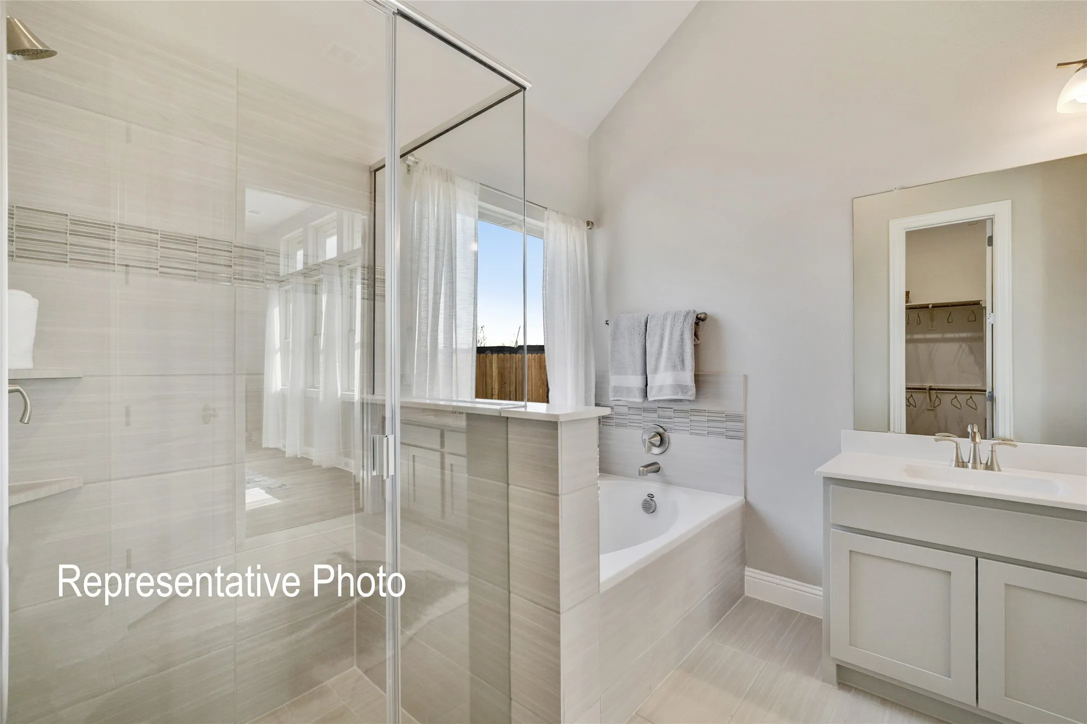 This bathroom features a contemporary design with a glass-enclosed shower, a built-in bathtub, and a vanity with a white countertop