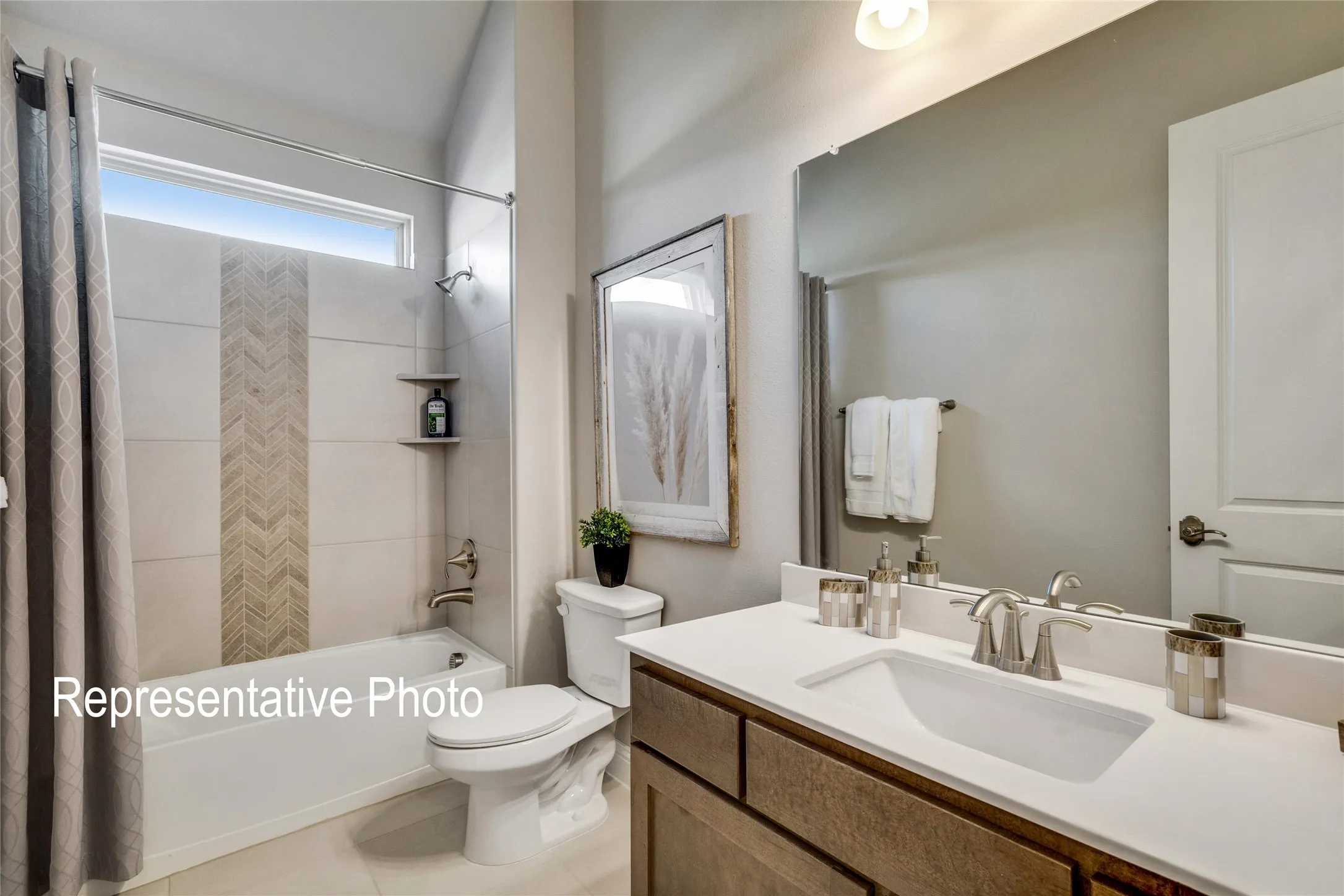 Bathroom featuring a bathtub with a tiled surround, a vanity with a white countertop and rectangular sink, and a large mirror