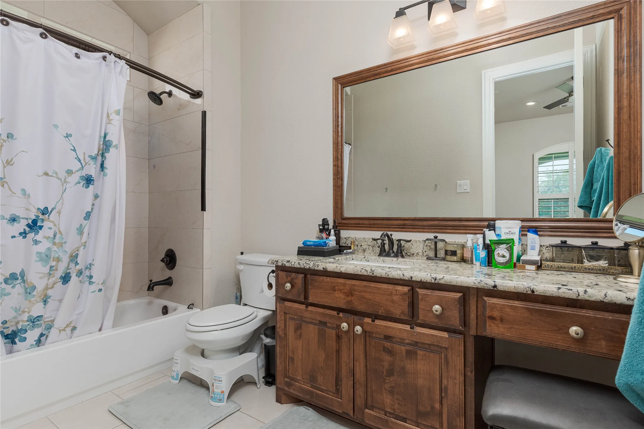 Bathroom with shower / tub combo, toilet, vanity, and tile patterned flooring